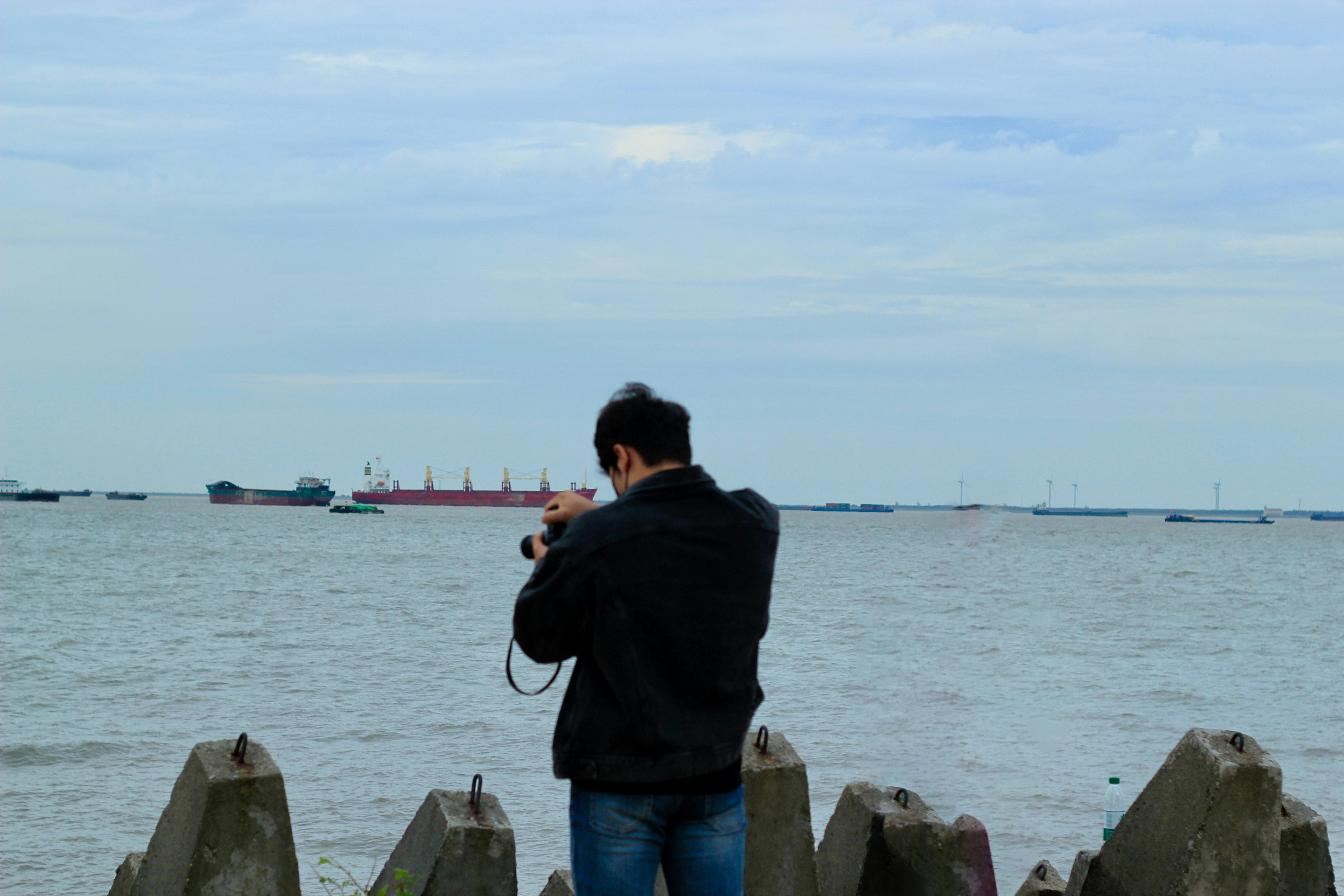 Hombre con cámara fotografía barco en el agua