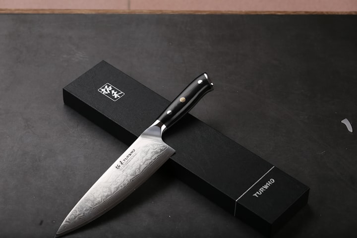 A polished chef's knife with a dark handle resting on its presentation box, evoking a single-bevel yanagiba slicer