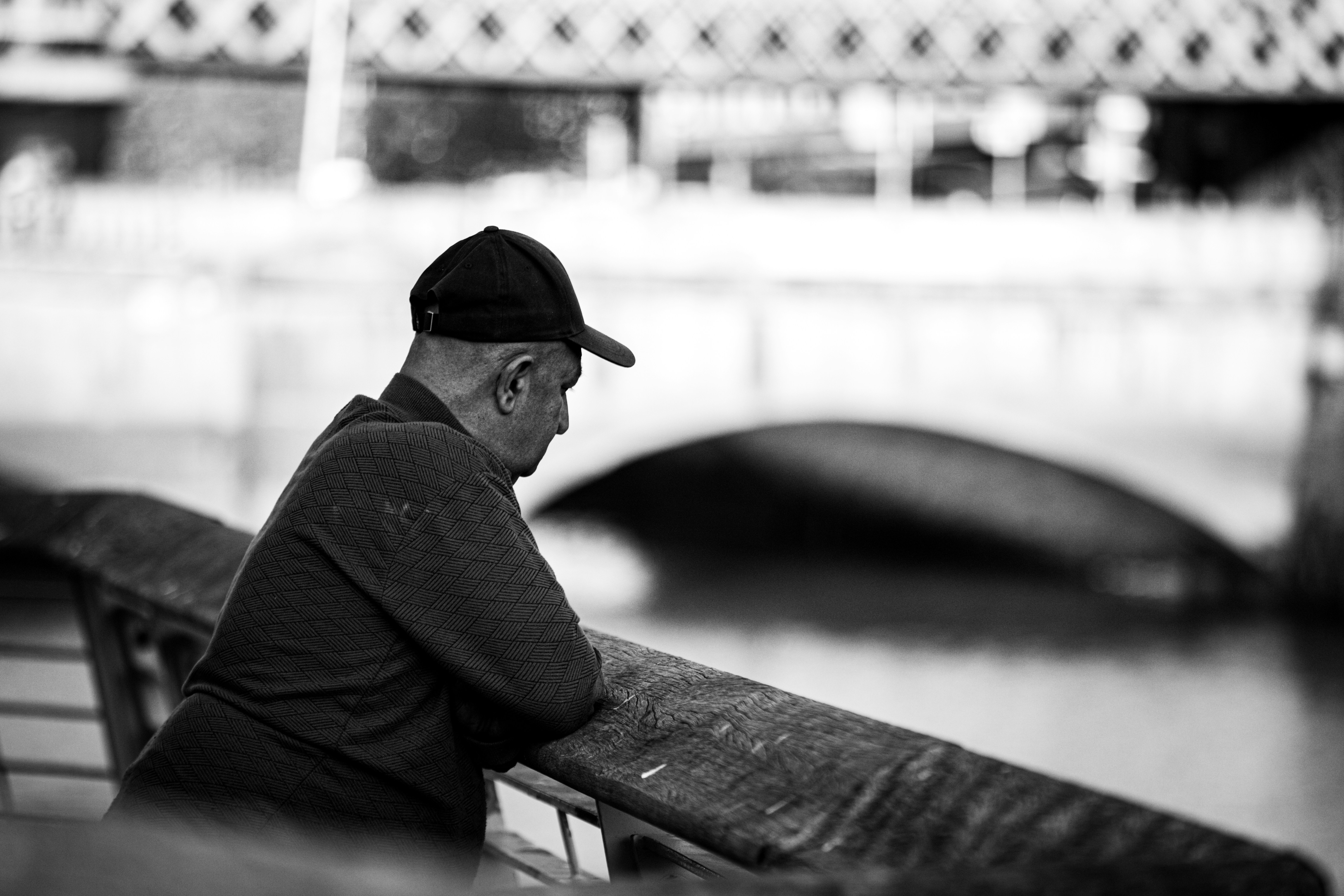 Hombre con gorra de béisbol mirando hacia abajo junto al agua