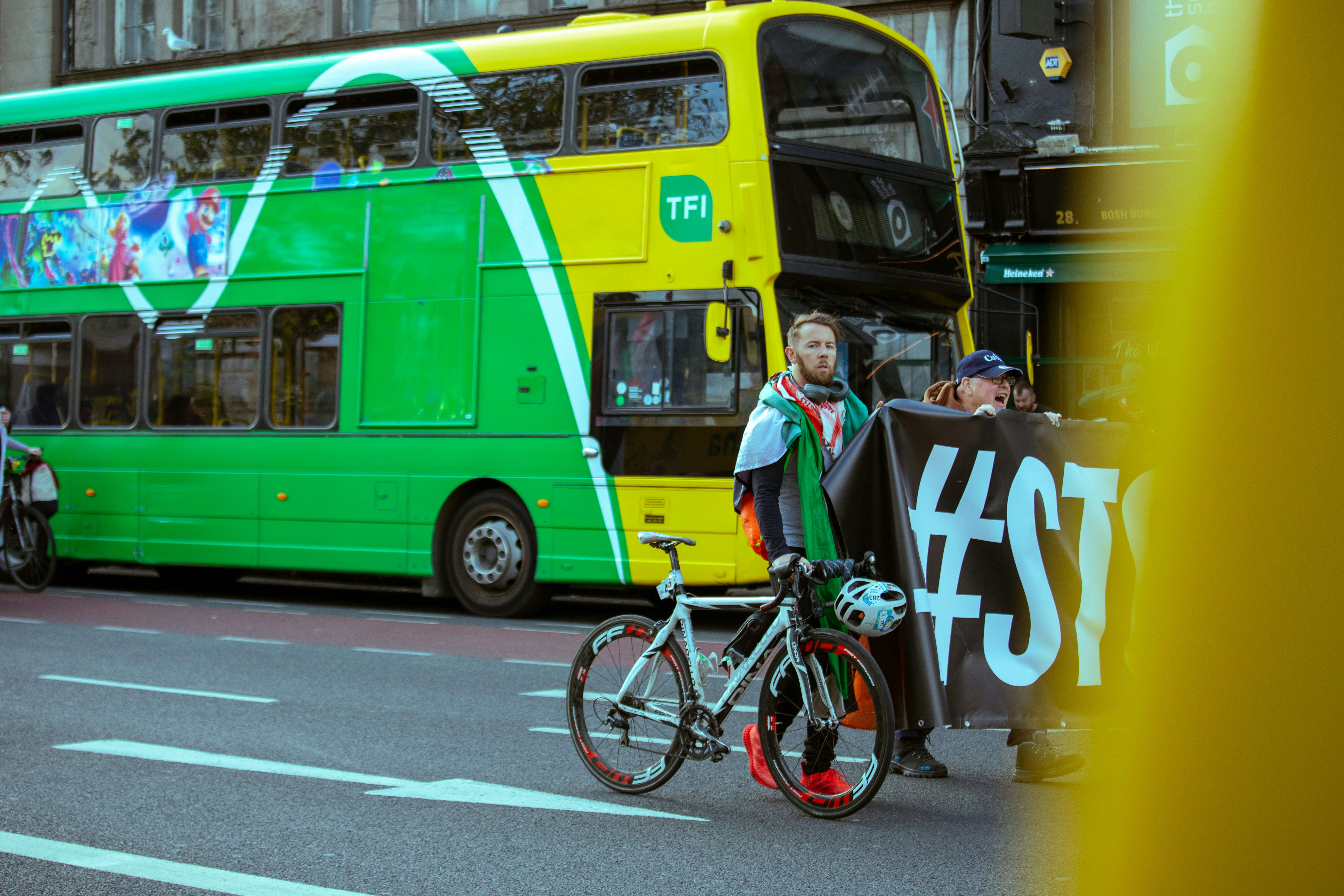 Personas con bicicletas y pancartas cerca del autobús de dos pisos