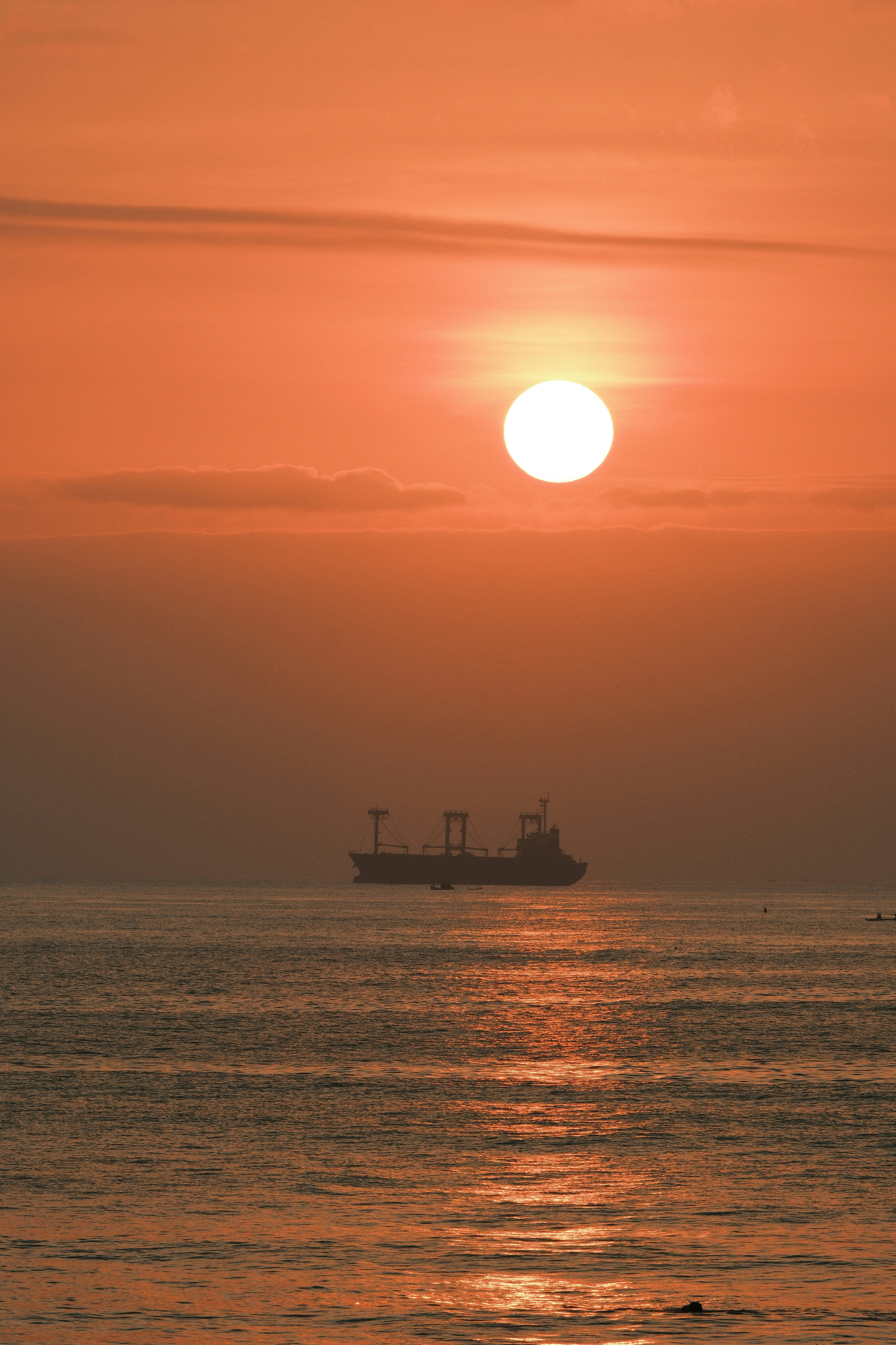 Cargo ship sailing on the ocean at sunset