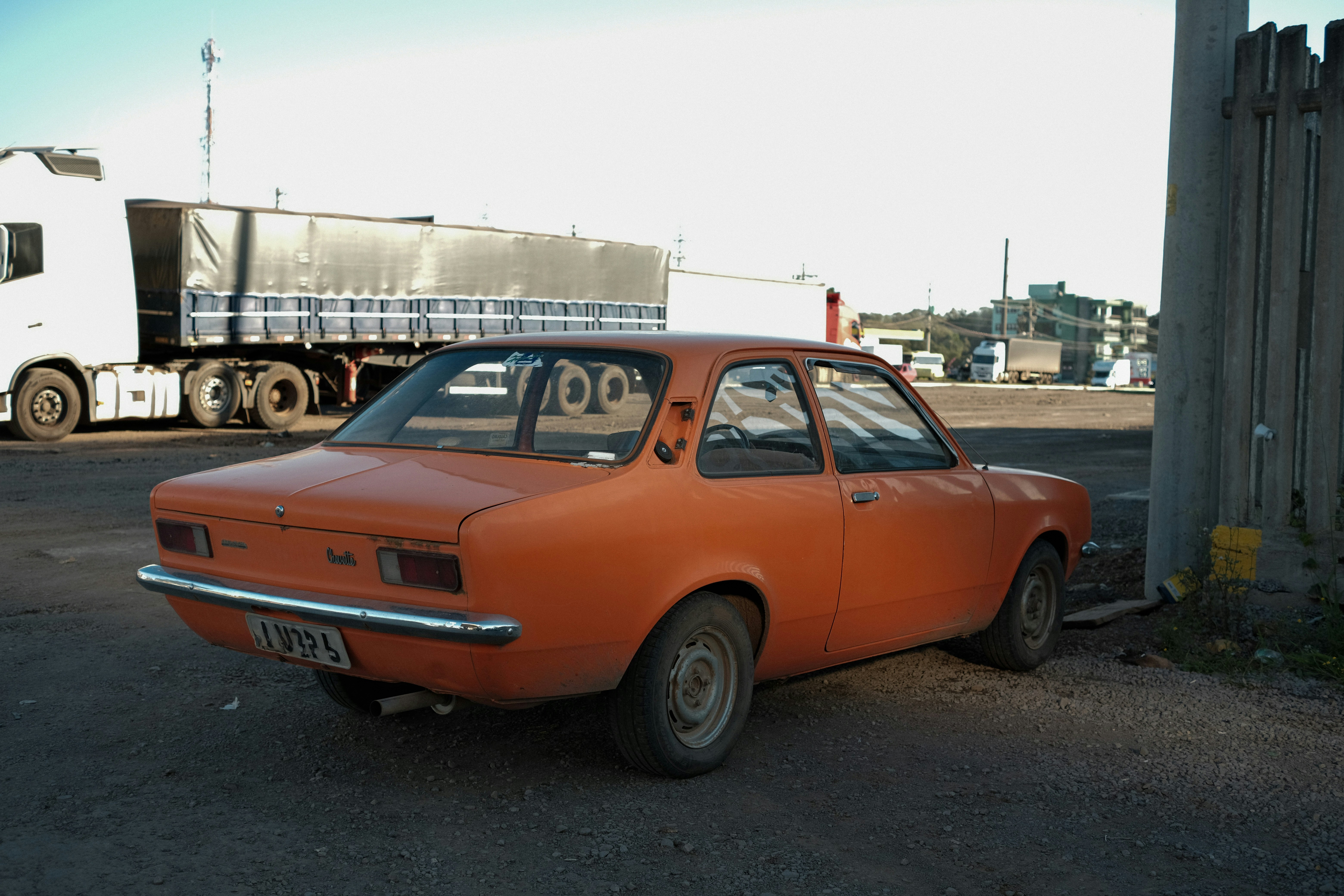 Oranger Oldtimer, der neben einem LKW geparkt ist