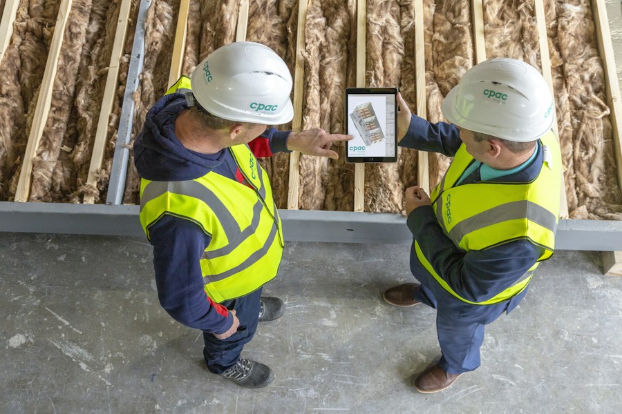 Two construction workers reviewing plans on a tablet at a job site