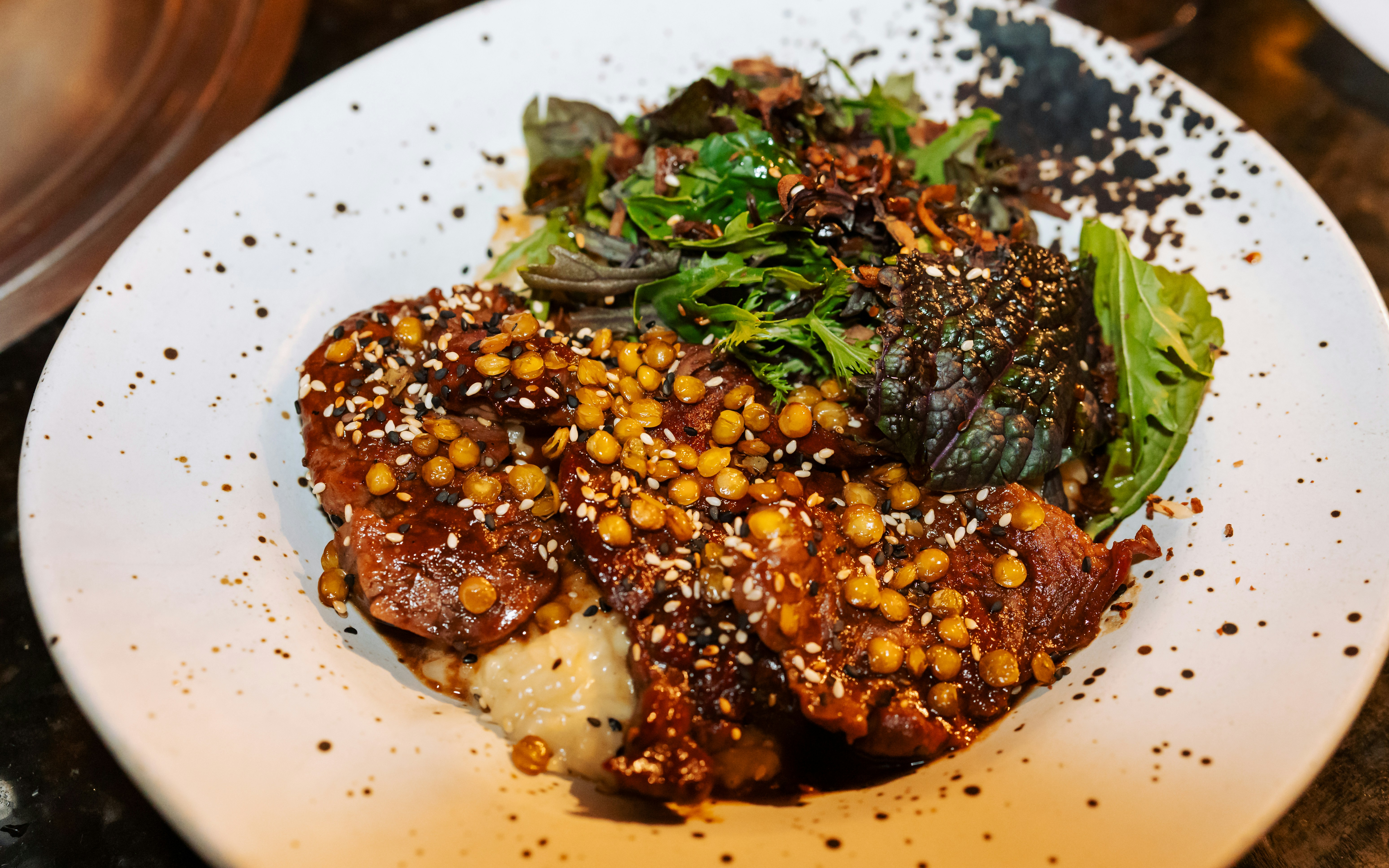 Gourmet dish with meat, grains, and greens.