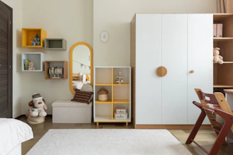 A child's bedroom with white and yellow furniture.