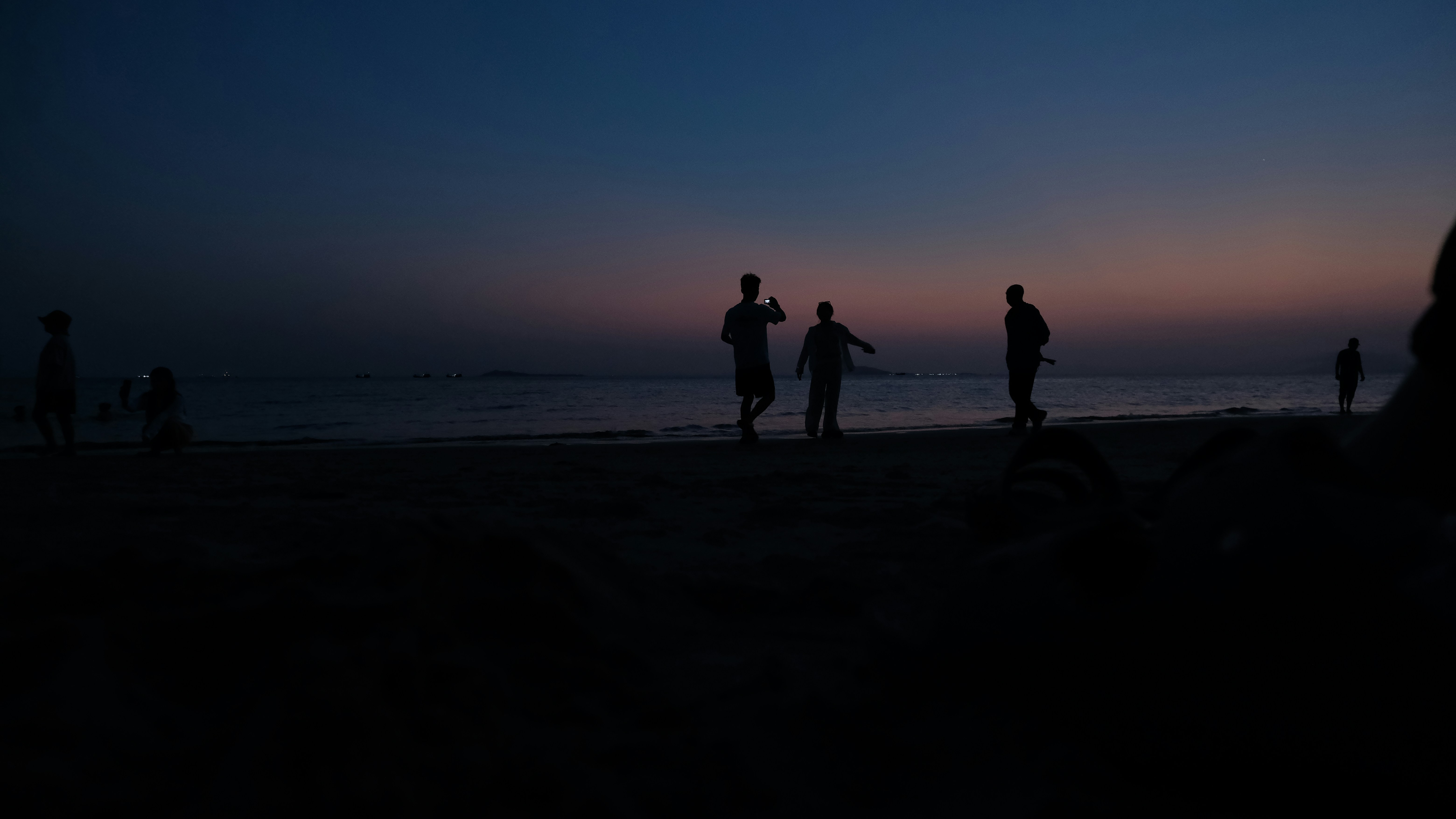 Silhouettes of people on a beach at dusk