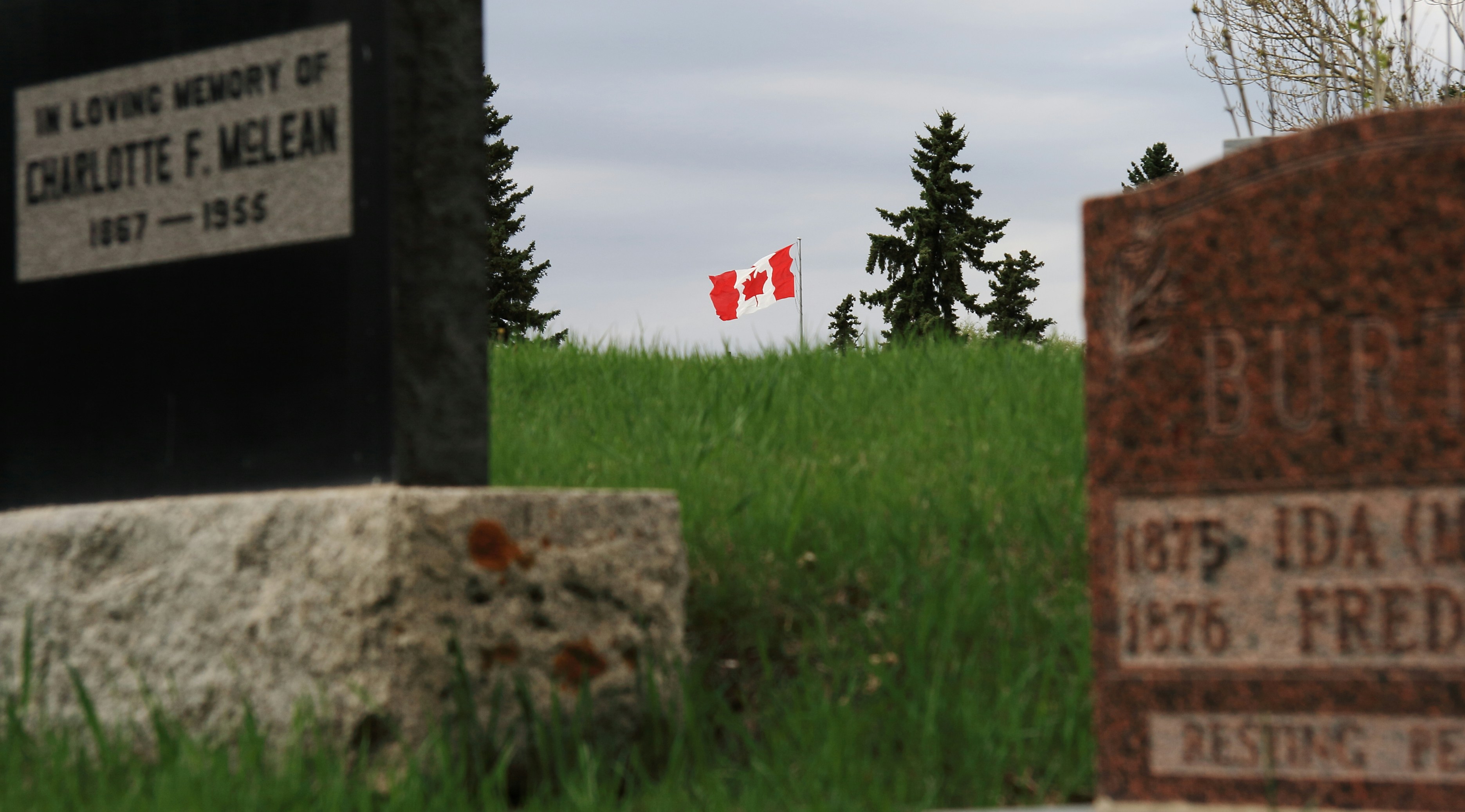Canadian flag flies over a grassy cemetery