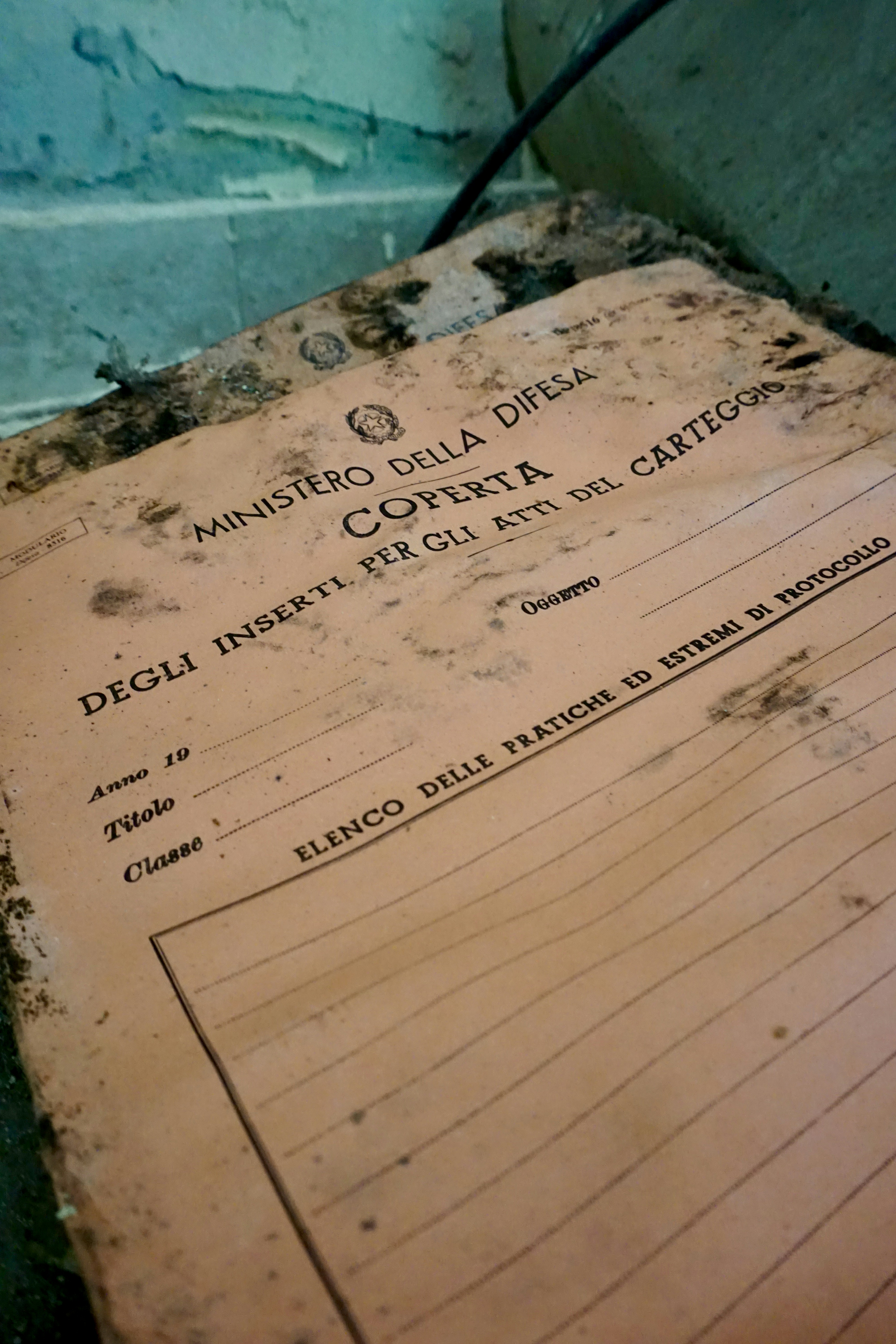 Documento velho e gasto com texto italiano em uma prateleira