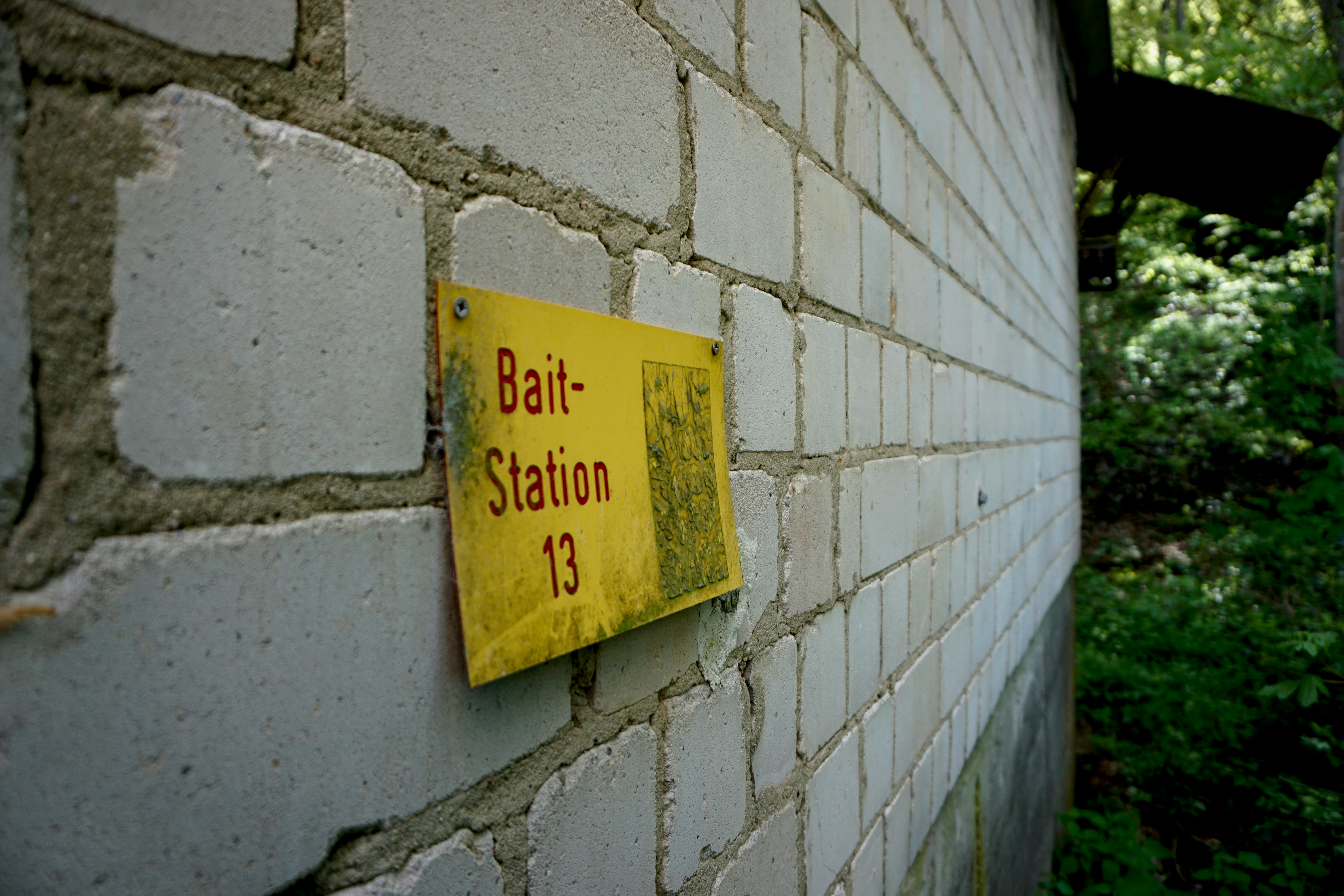 Yellow sign on brick wall reads bait-station 13
