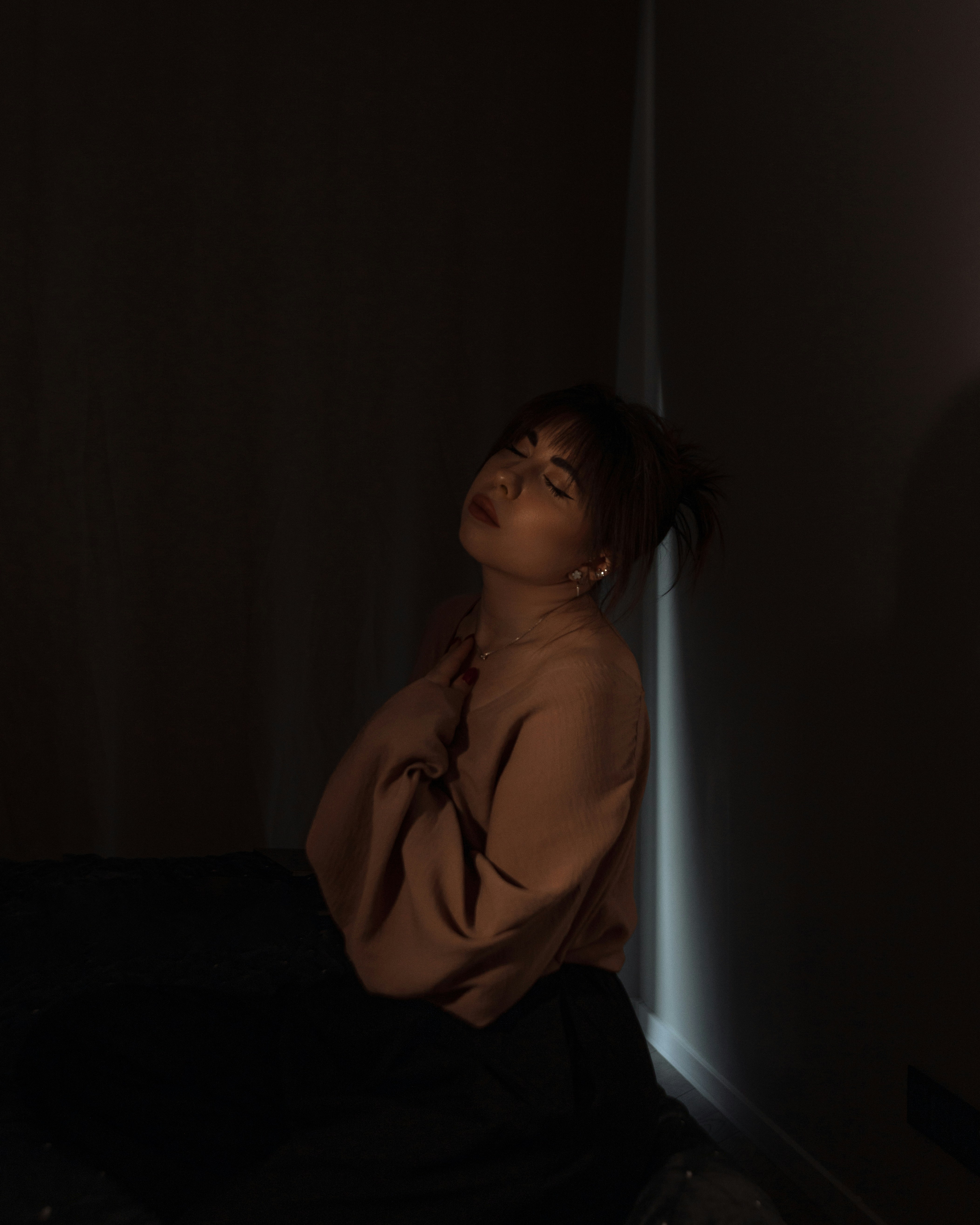 Woman leaning against a dimly lit corner wall