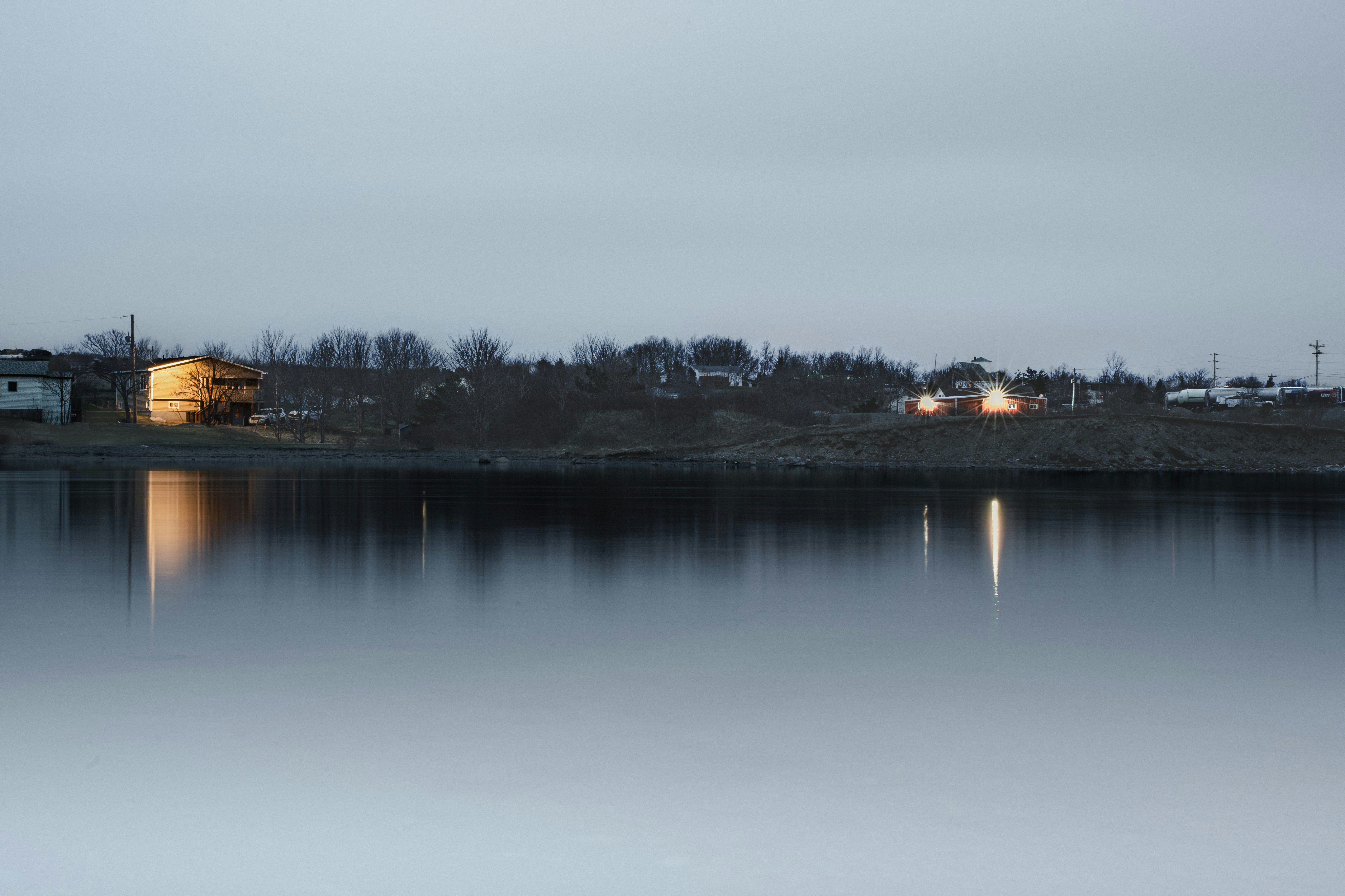Luces lejanas de los pueblos reflejadas en el agua tranquila al anochecer