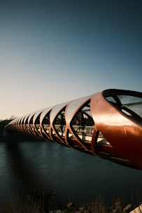Modern curved bridge over dark water under clear sky