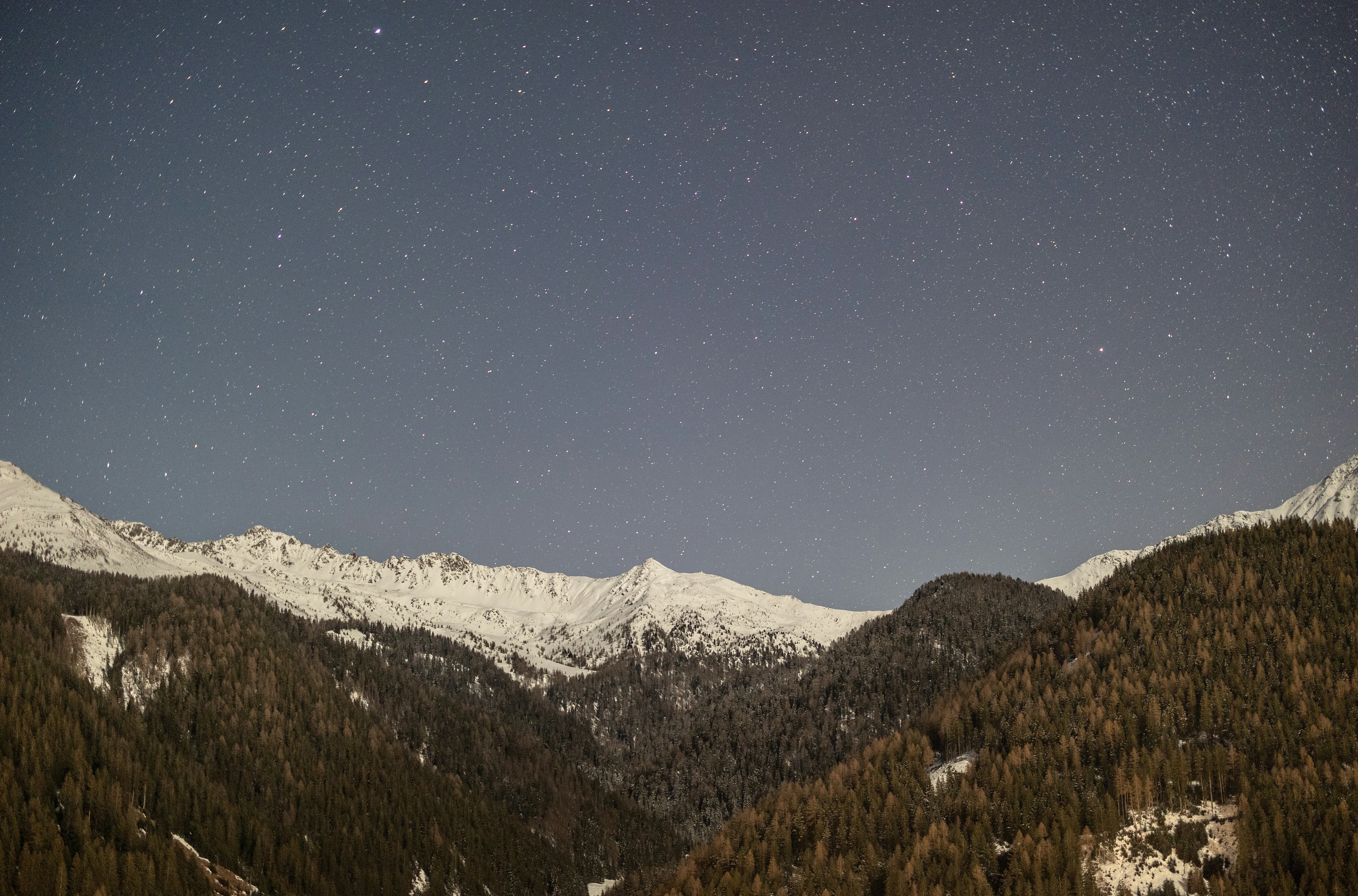 Snowy mountain peaks under a starry night sky