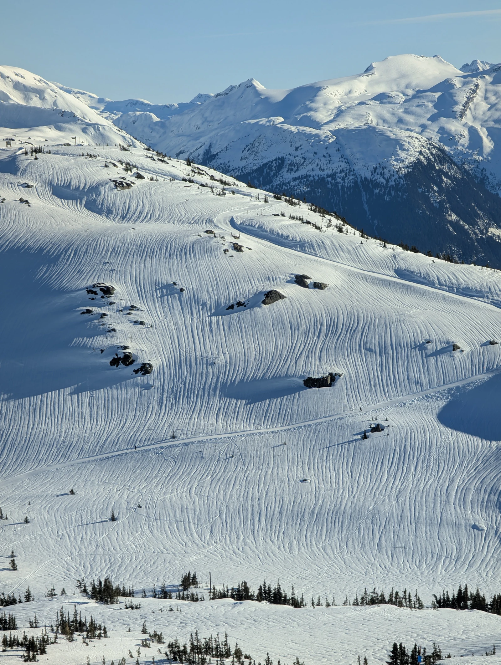 Snowy mountain slope with ski tracks and distant peaks near Whistler, BC