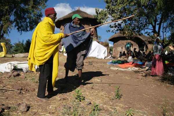 Two men with sticks in a village setting — Lalibela, Ethiopia