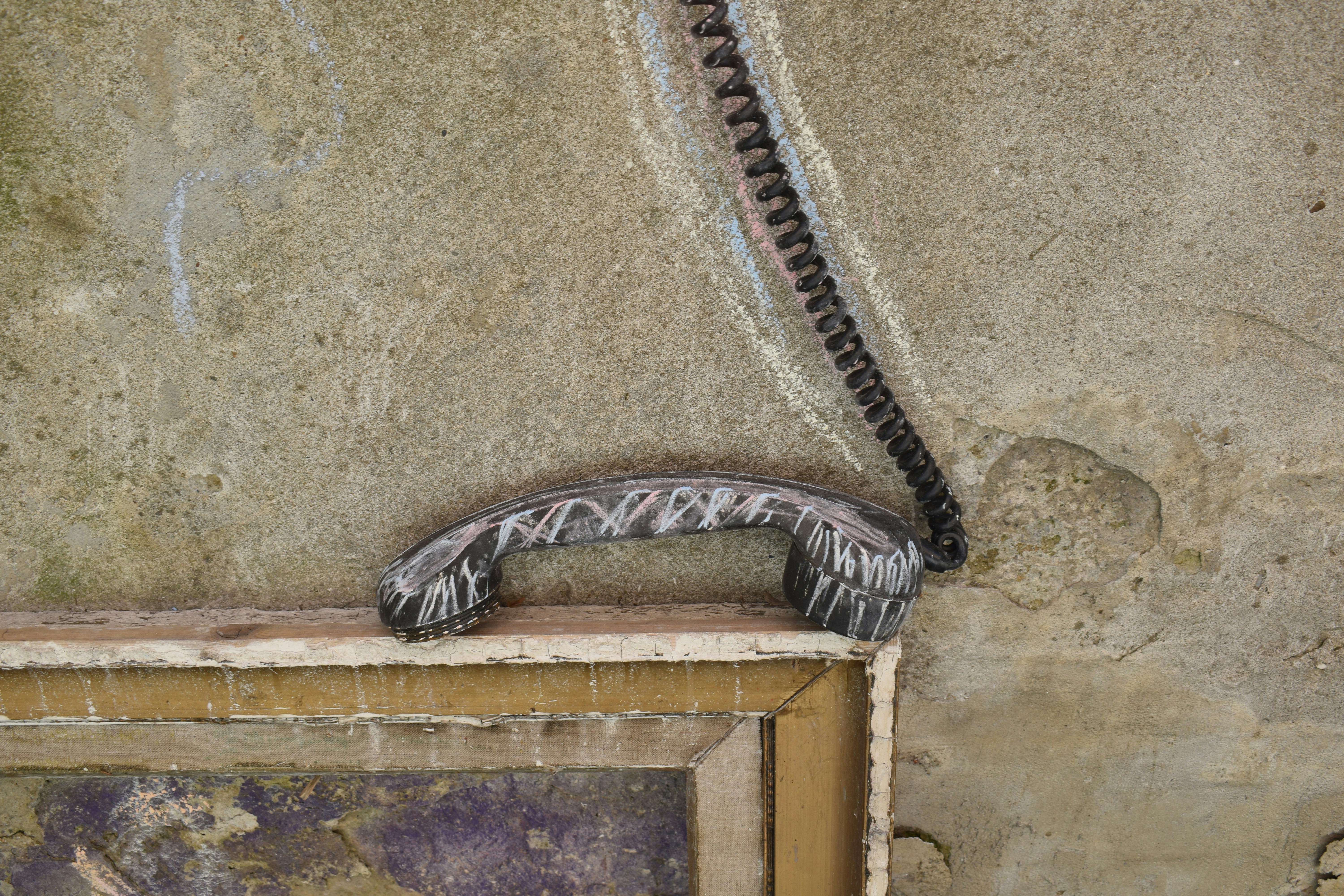 A close-up of a vintage telephone receiver on a wall.