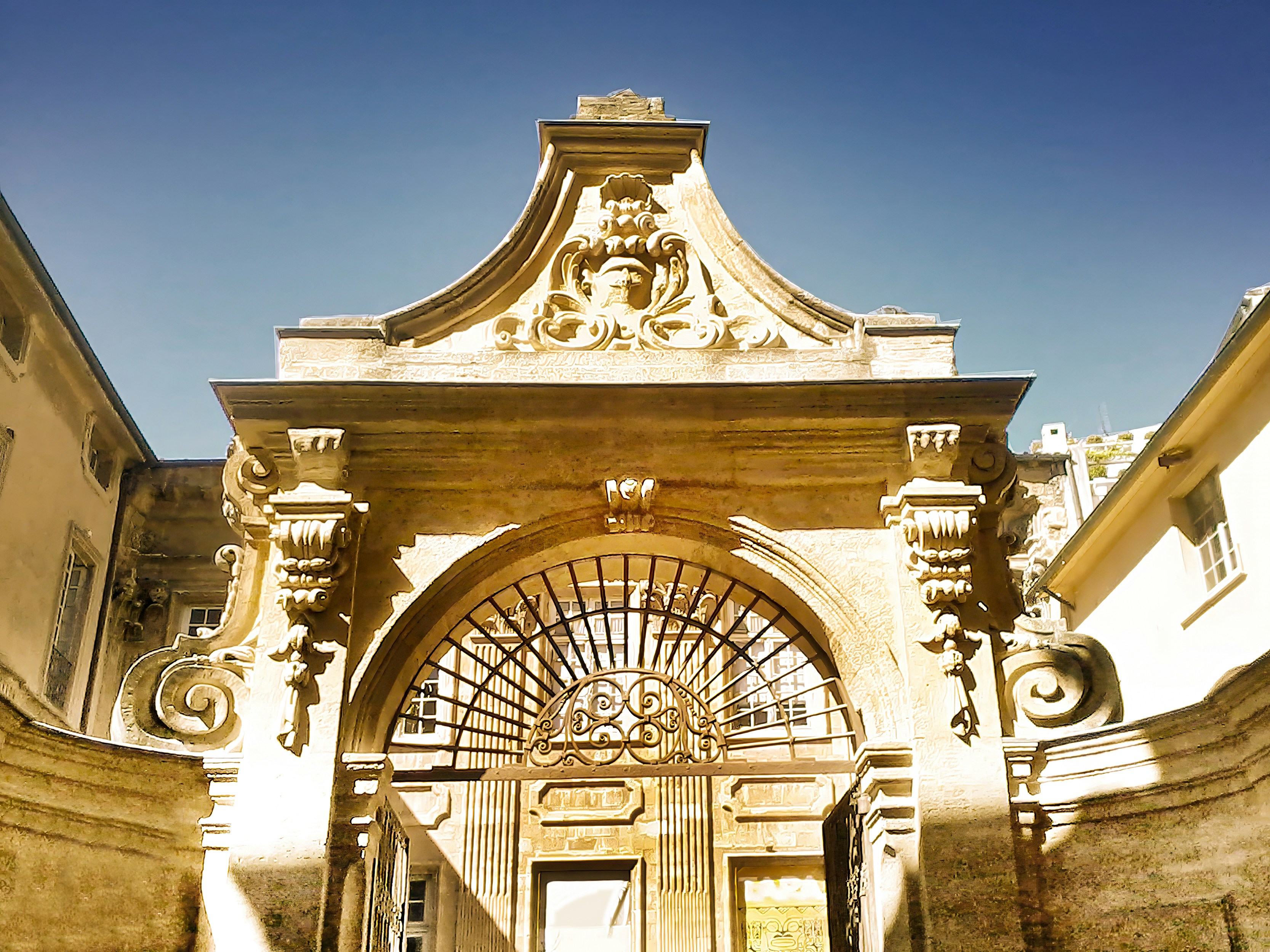 Ornate stone archway with decorative carvings and metal gate.