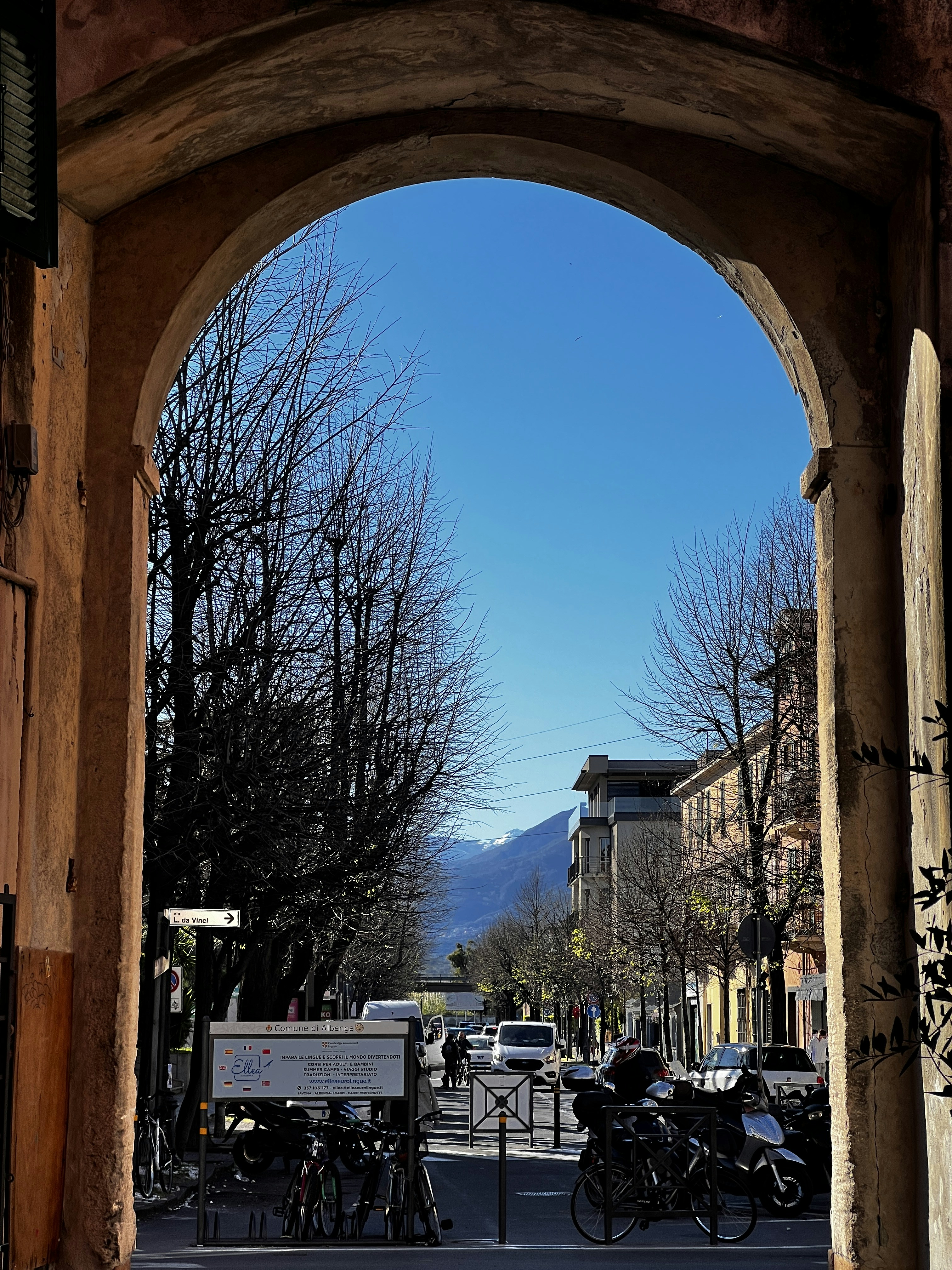 Blick durch einen Torbogen einer Straße mit kahlen Bäumen.