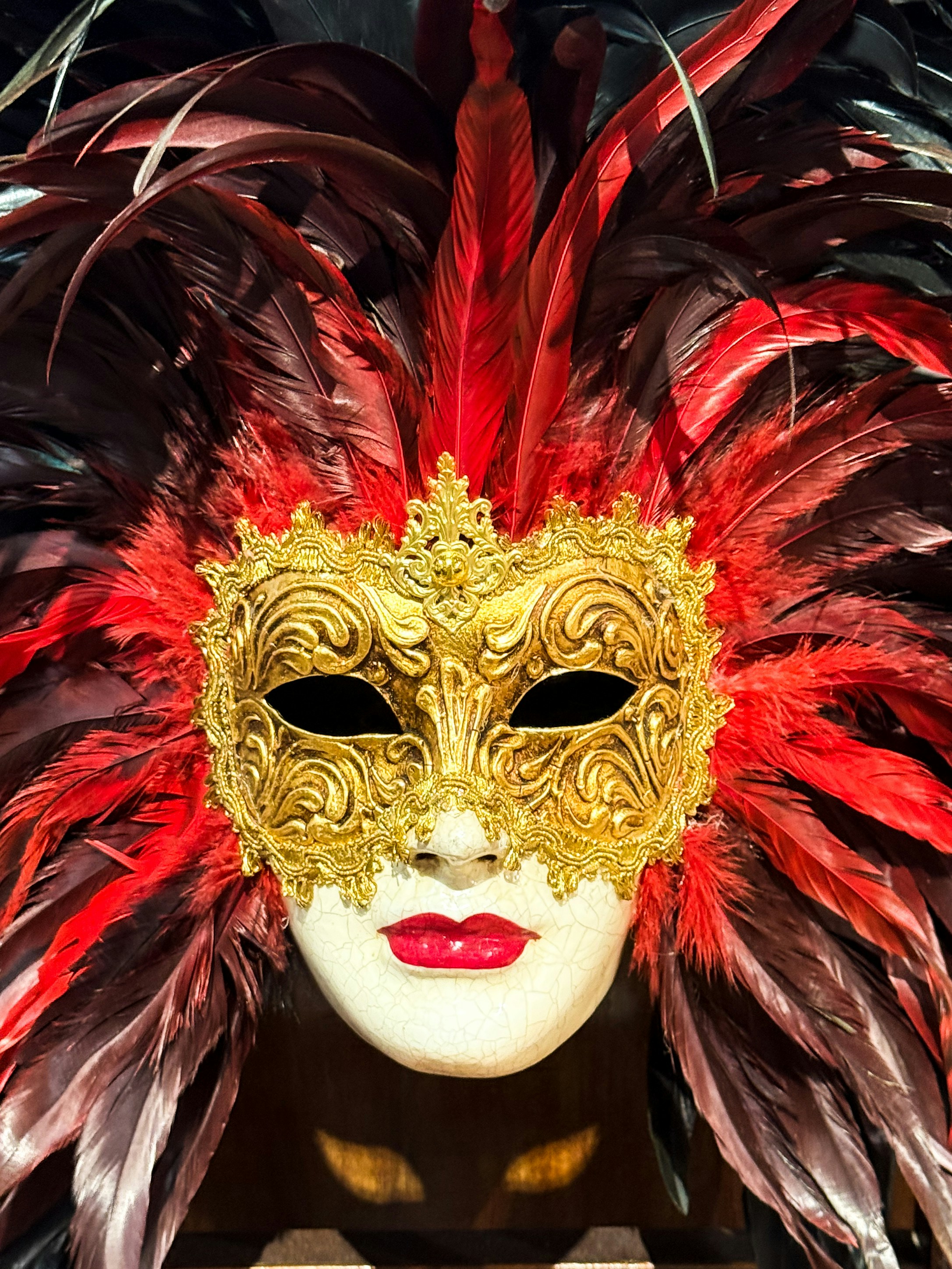 Masque masqué doré orné avec des plumes rouges
