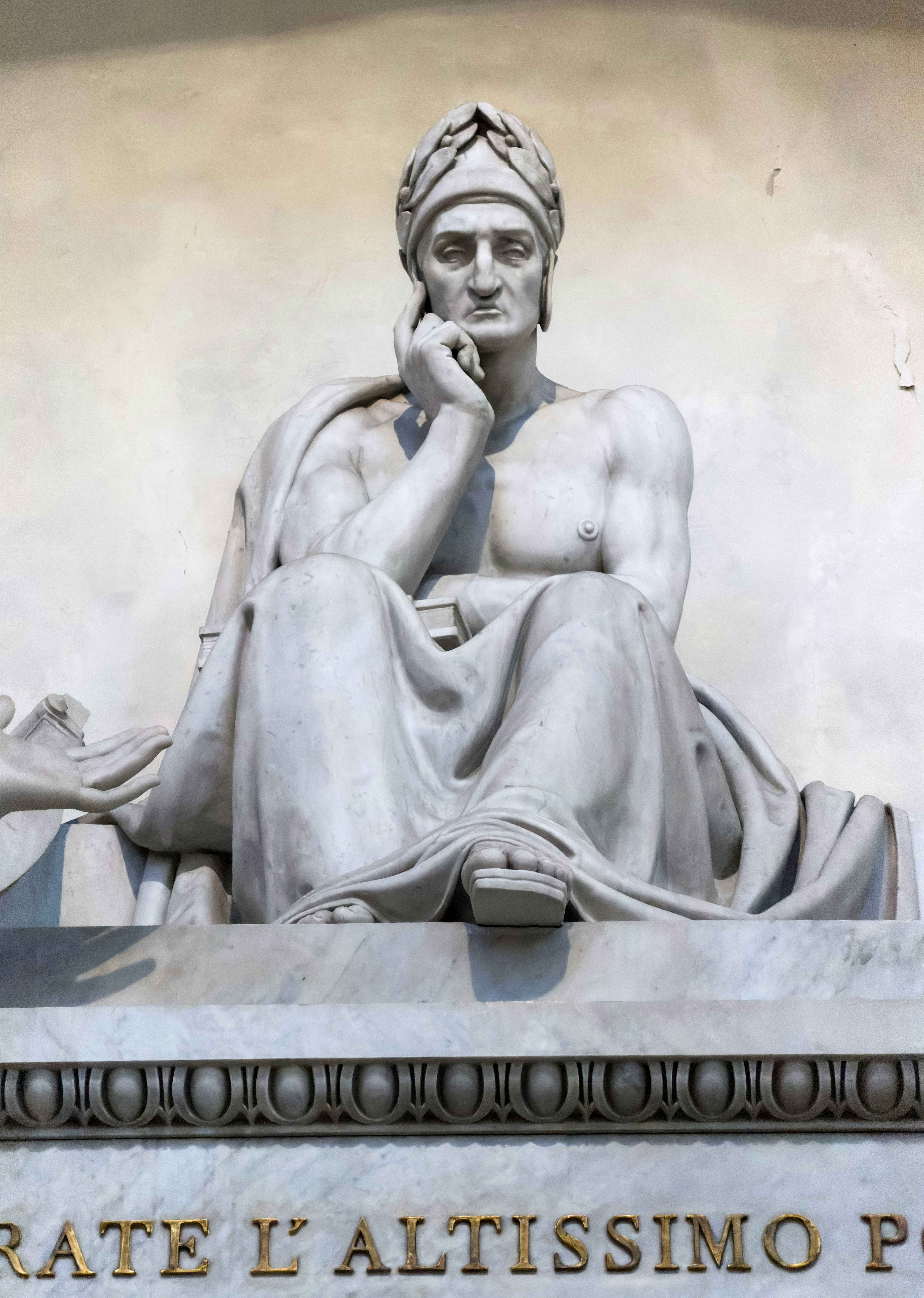 Statue en marbre d’un homme assis en tenue classique.
