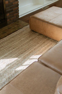 Tan leather sectional sofa and ottoman on rug