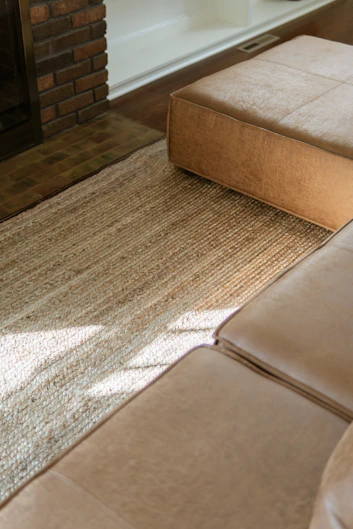 Tan leather sectional sofa and ottoman on rug