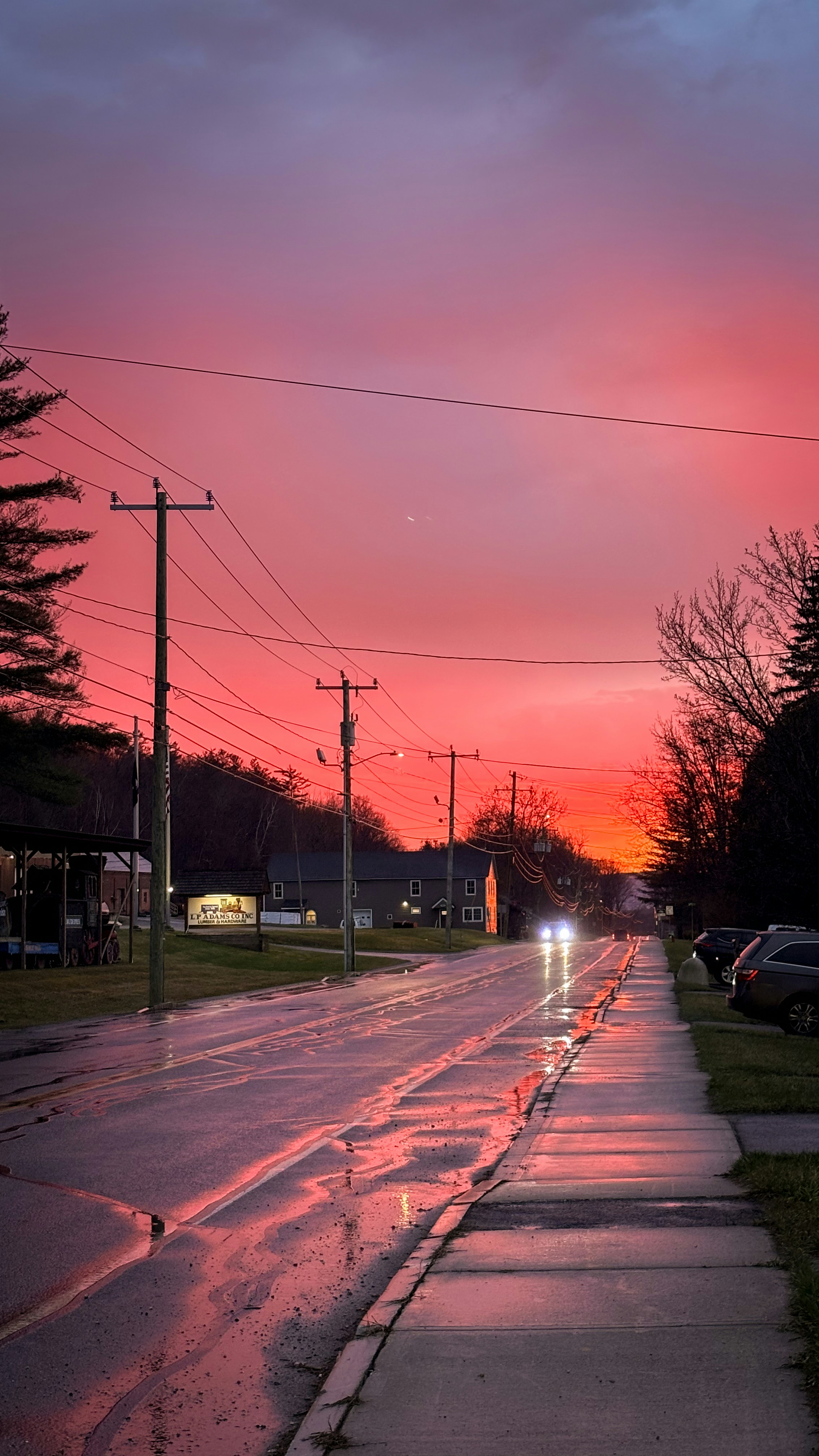 Vibrant sunset over a wet street with reflections.