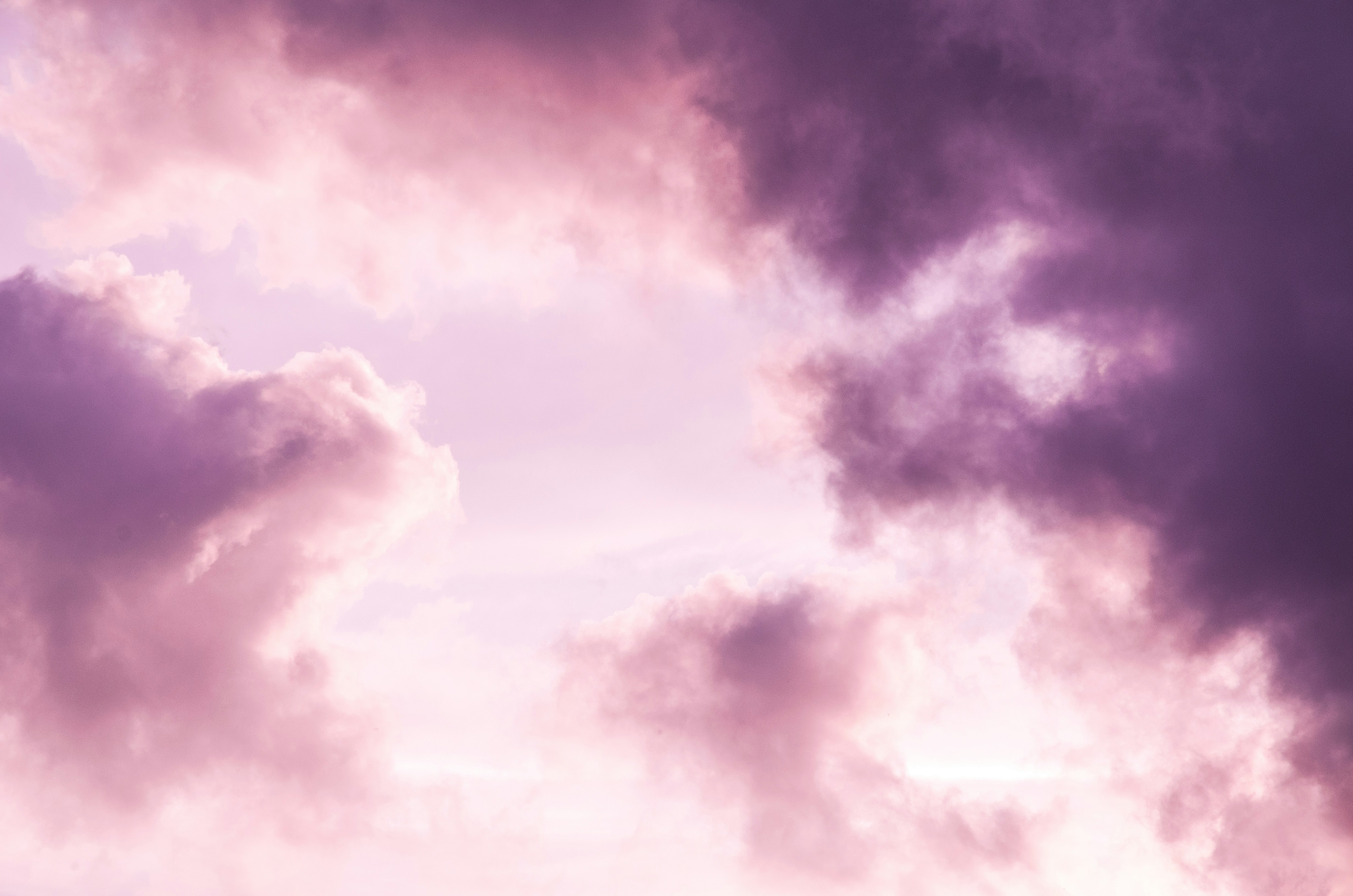 Rosa und violette Wolken vor einem hellen Himmel
