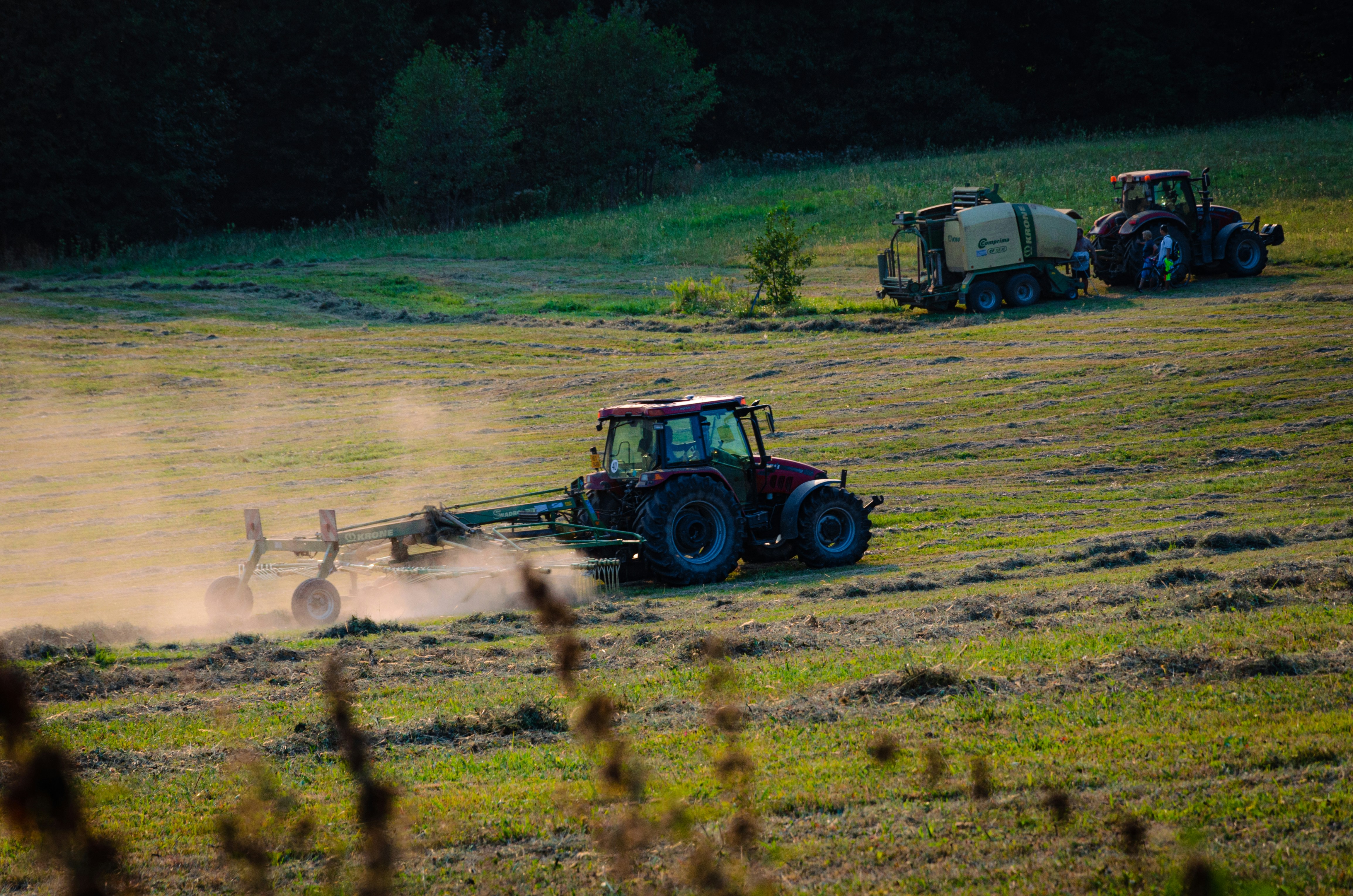 Traktoren, die bei Sonnenuntergang auf einem Feld arbeiten