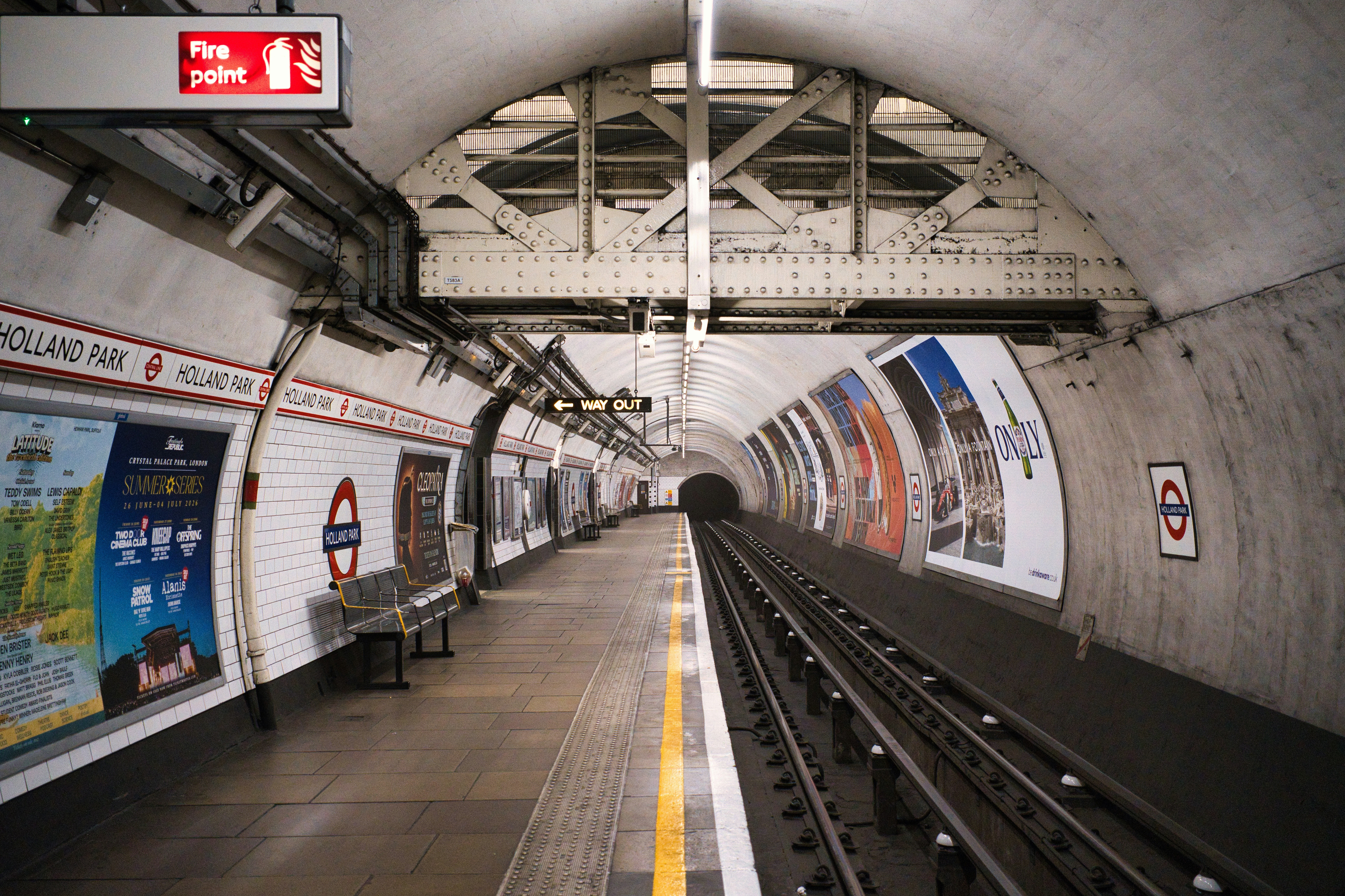 Plataforma vazia da estação de metrô com trilhos de trem e anúncios