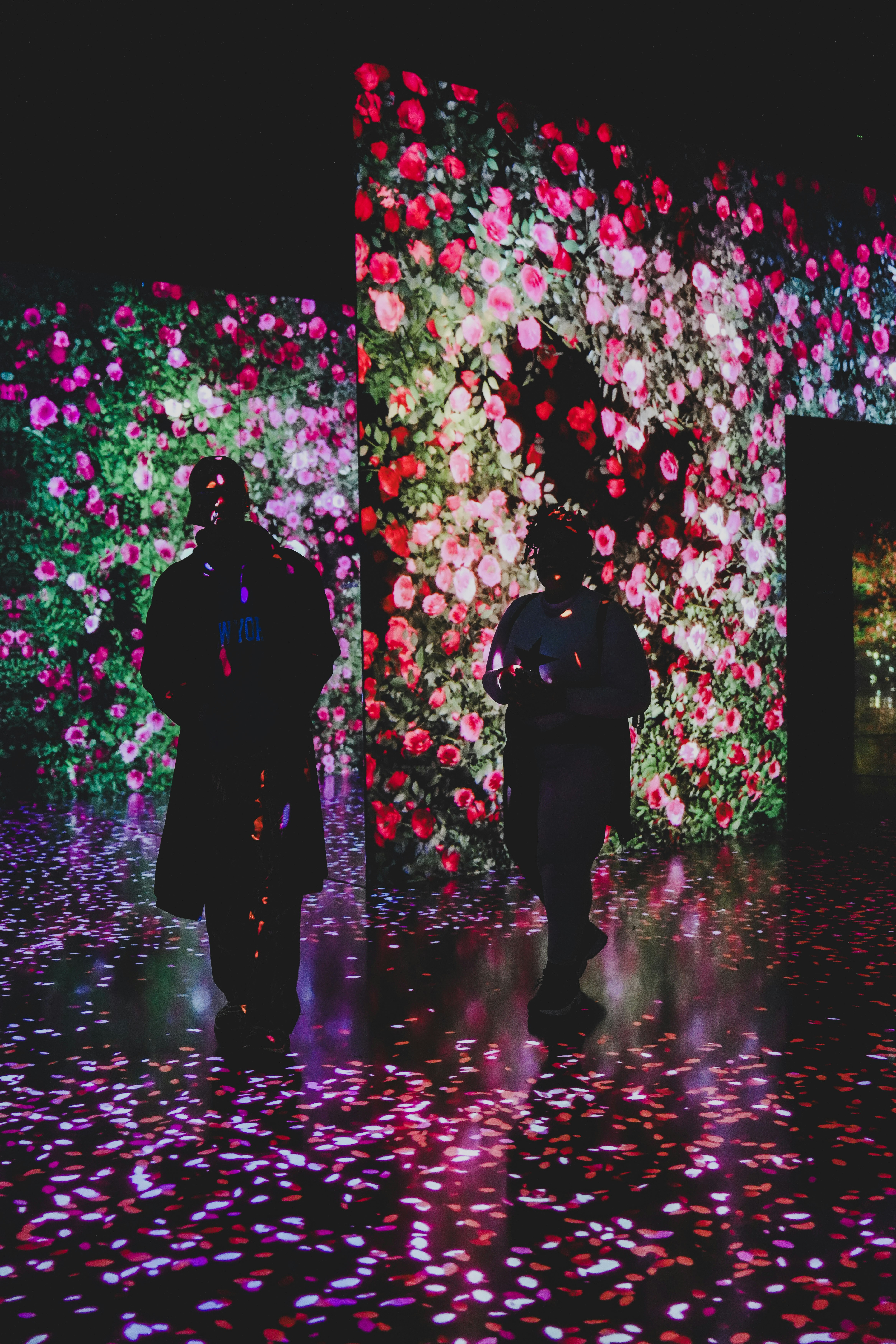 Dos personas atraviesan una sala con proyecciones florales