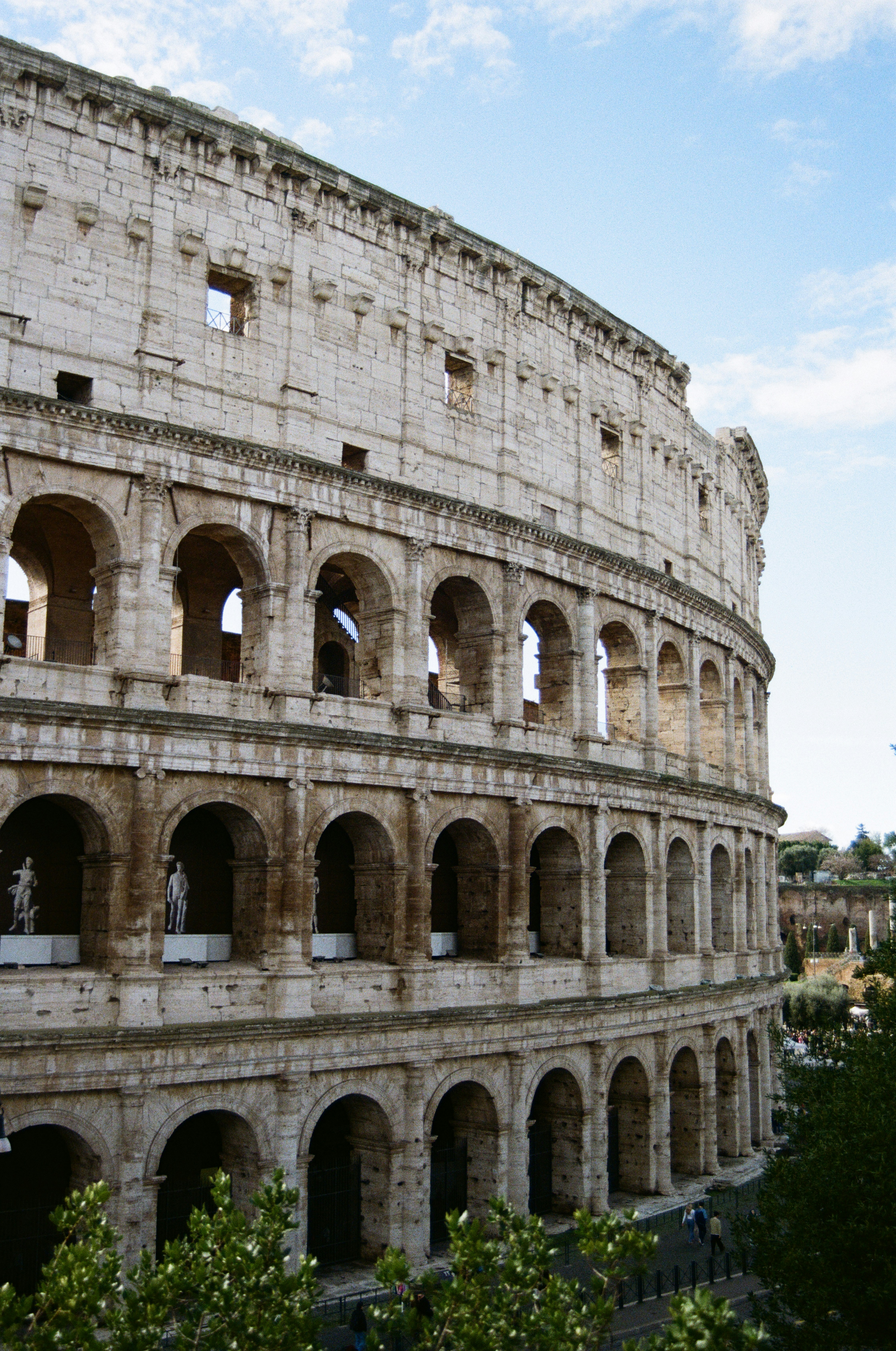 The ancient roman colosseum stands under a blue sky.
