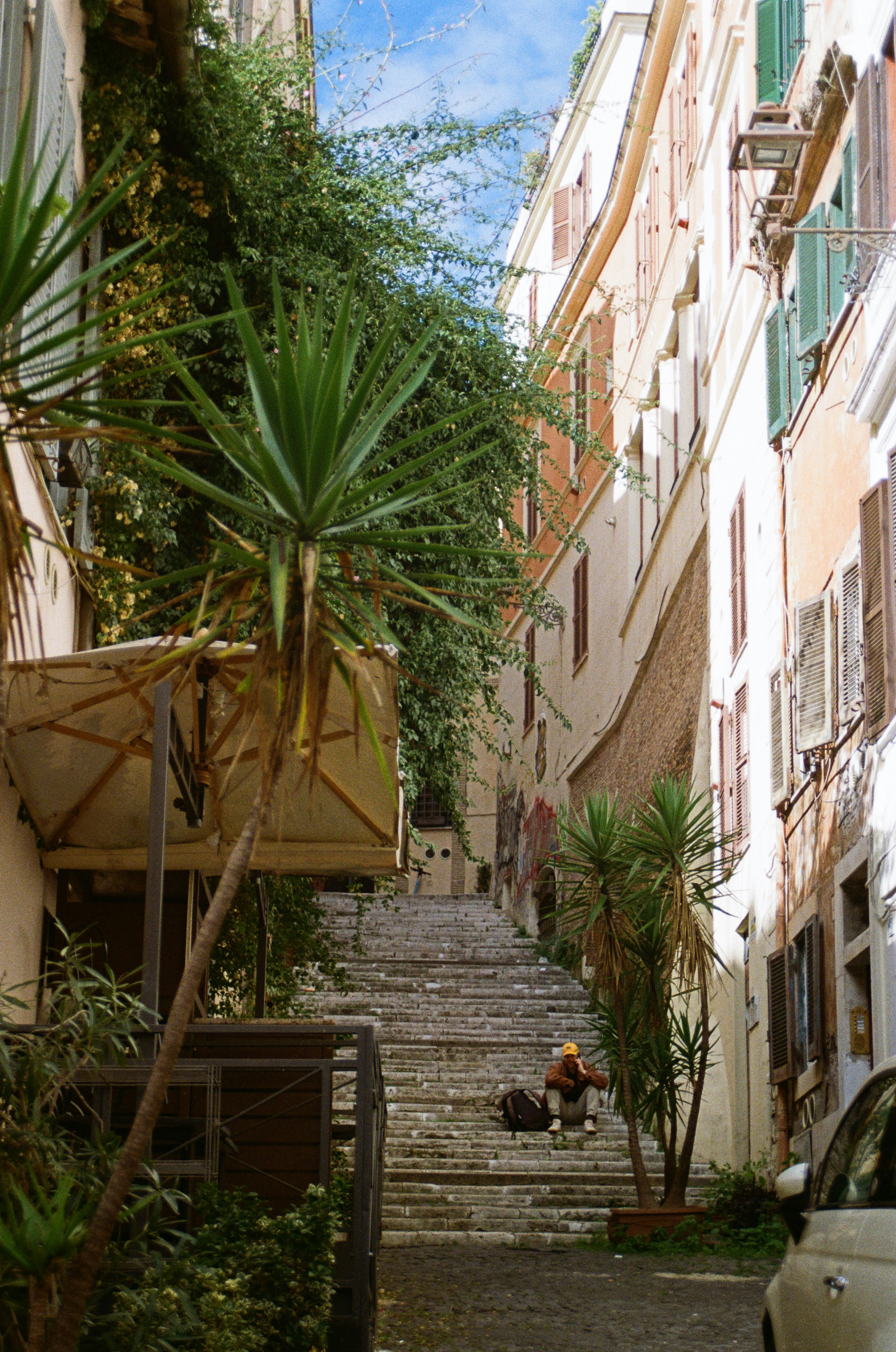 Person sitting on steps of a narrow italian street