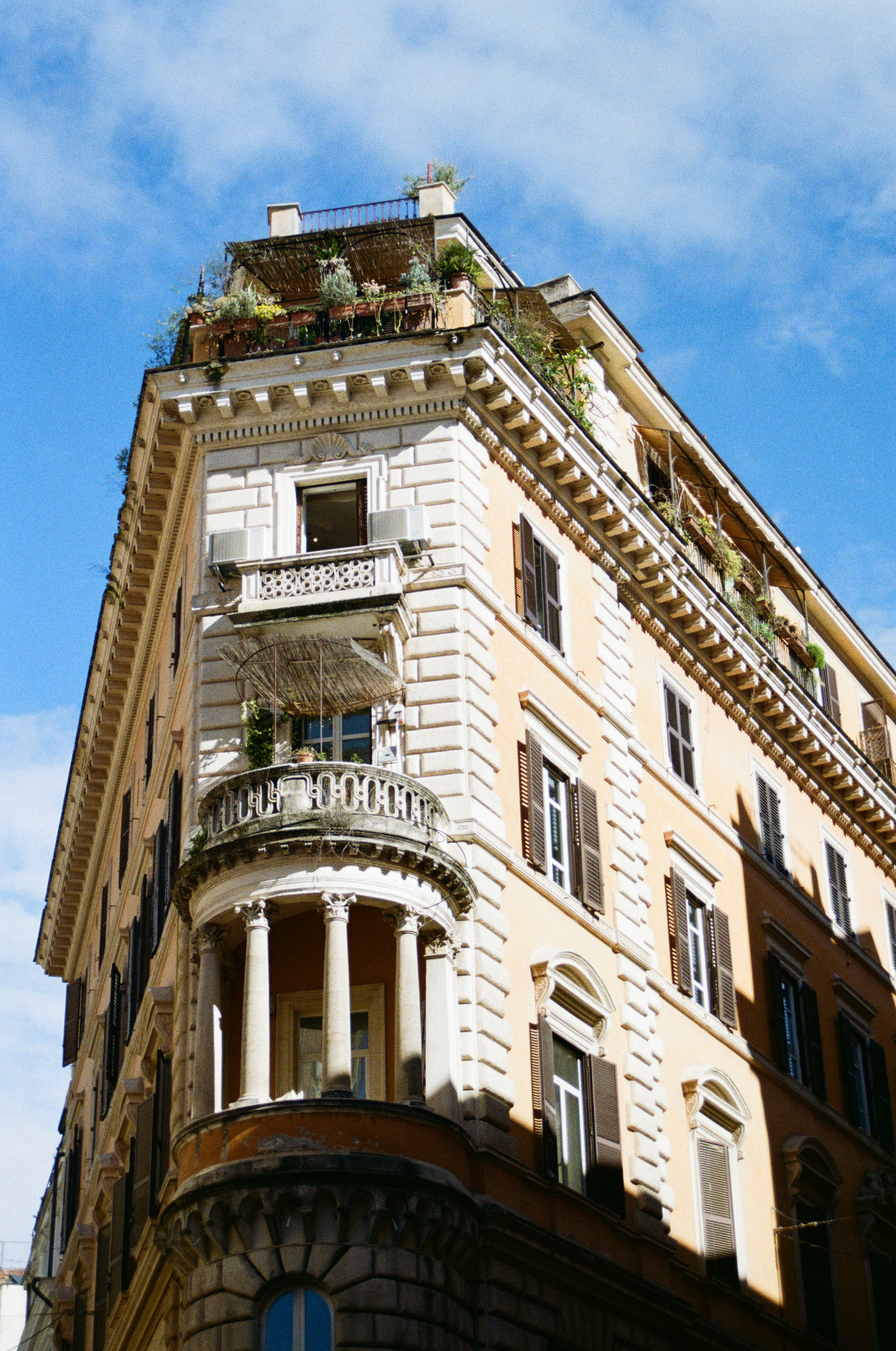 Corner view of an ornate building with balconies and plants.