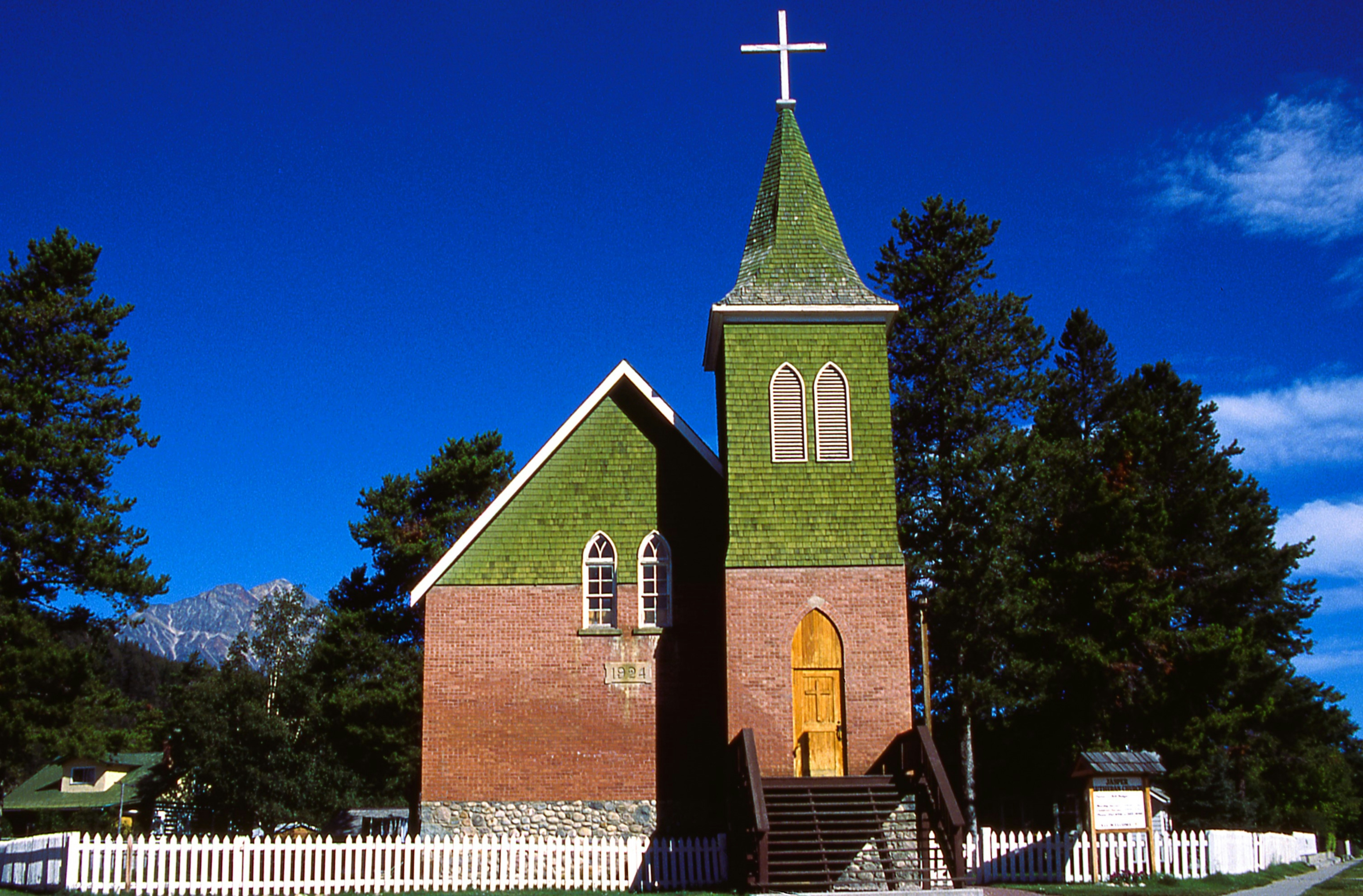 Brick church with green roof and steeple