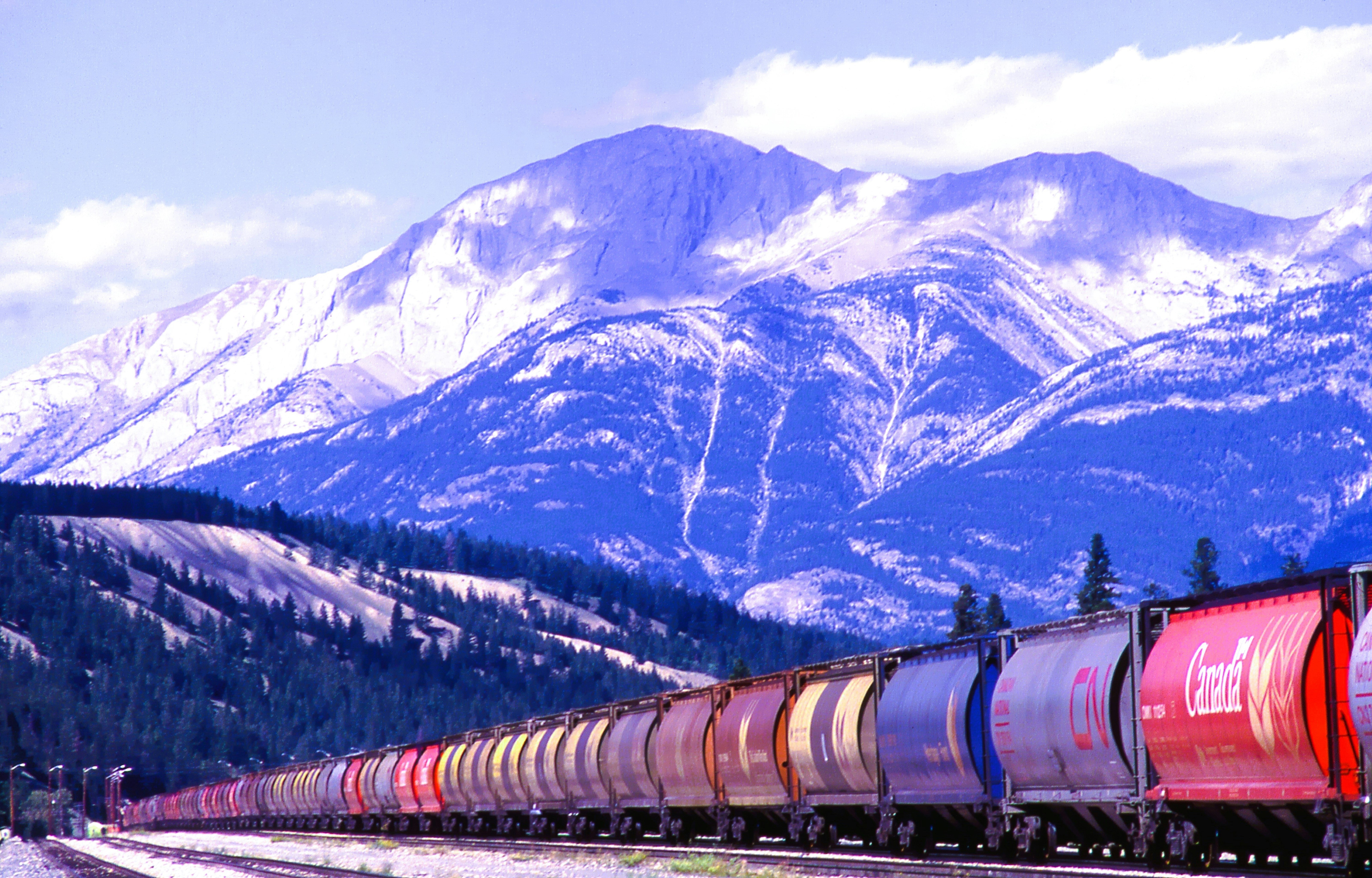 Freight train moves past snow-covered mountains