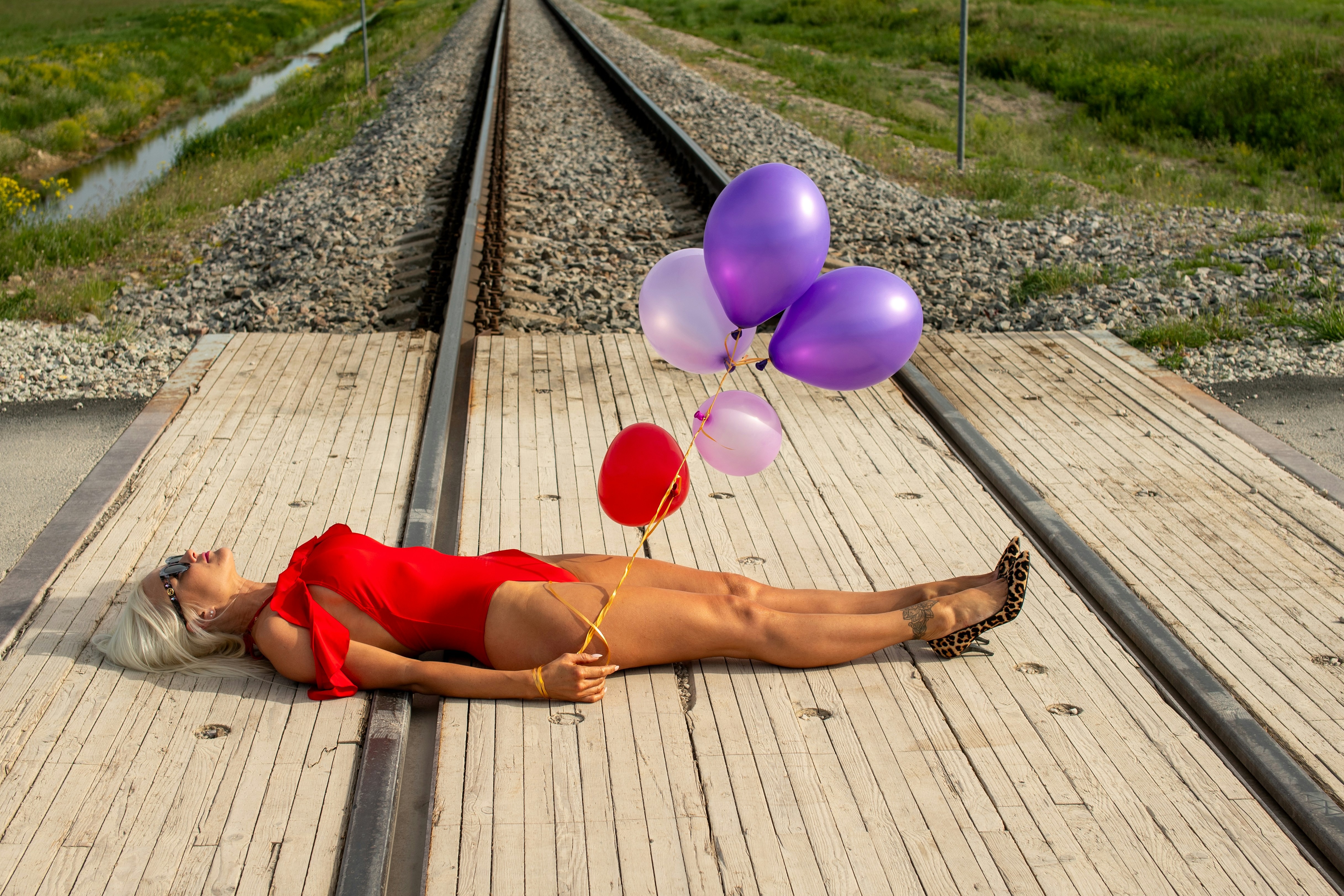 Wanita berbaring di rel kereta api dengan balon