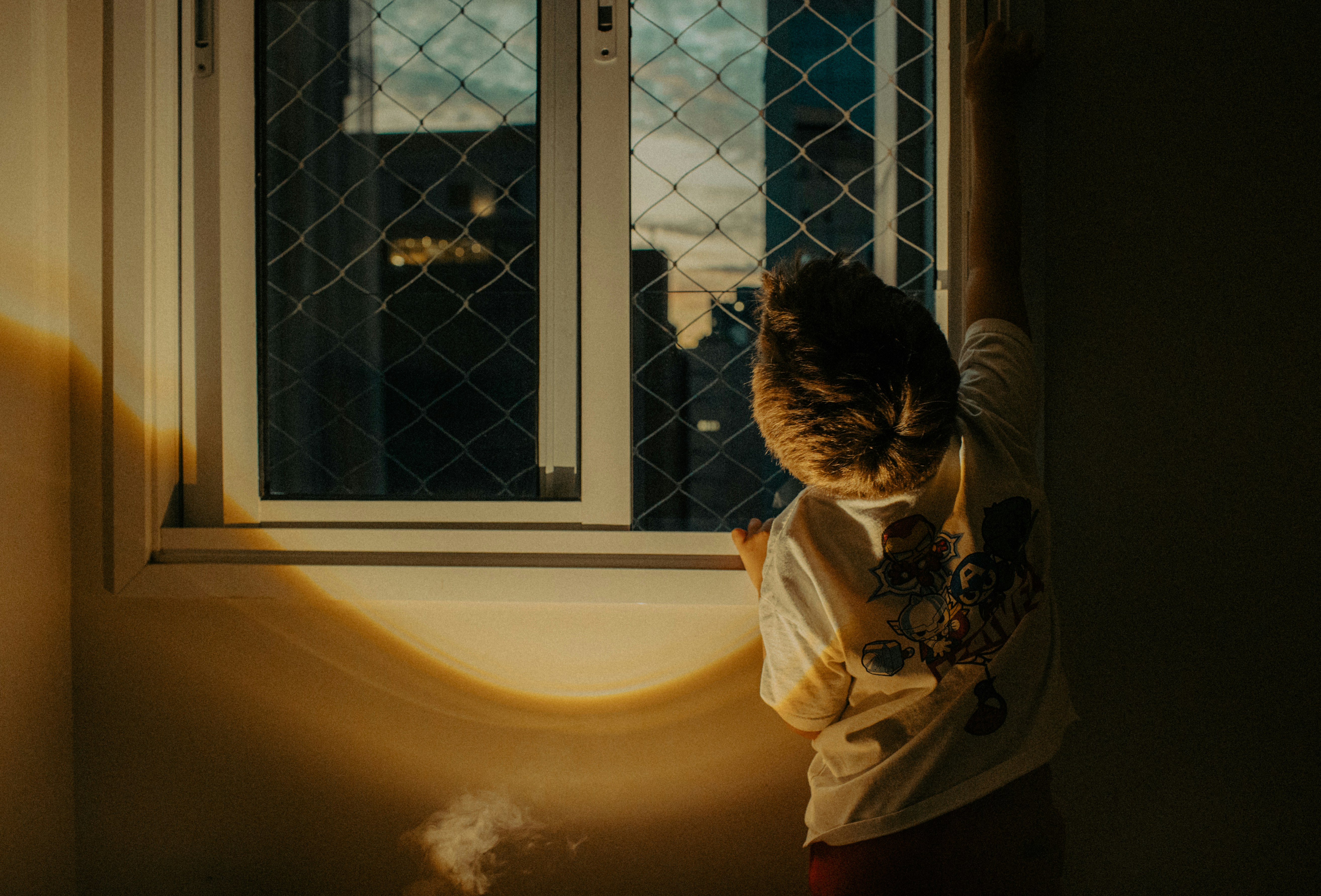 Person looking out a window at sunset