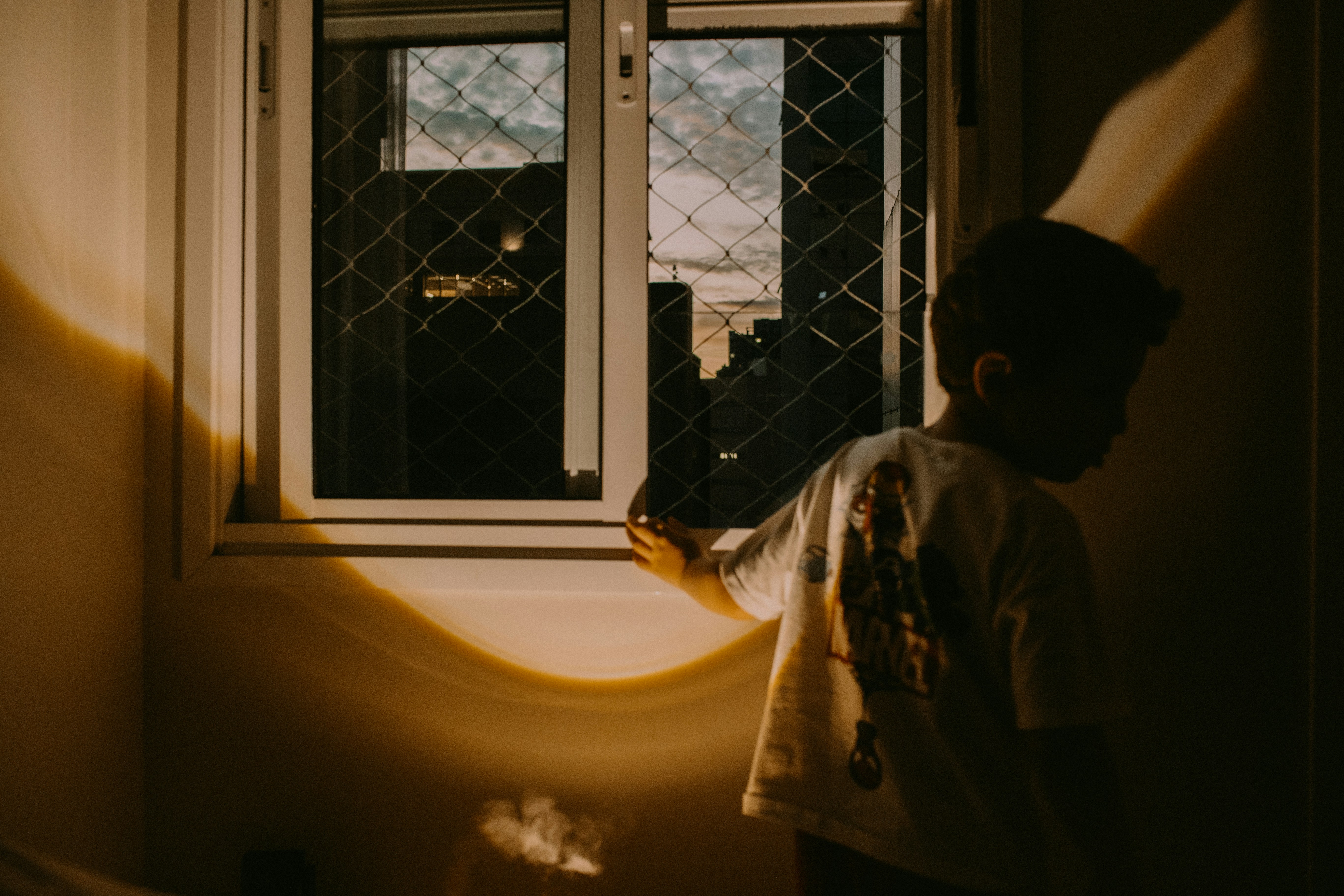 Boy looking out a window with warm light
