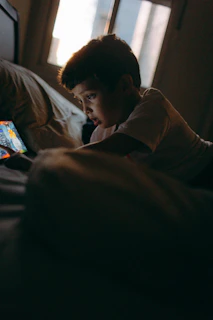 Boy lying on bed looking at tablet screen