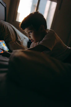 Boy lying on bed looking at tablet screen