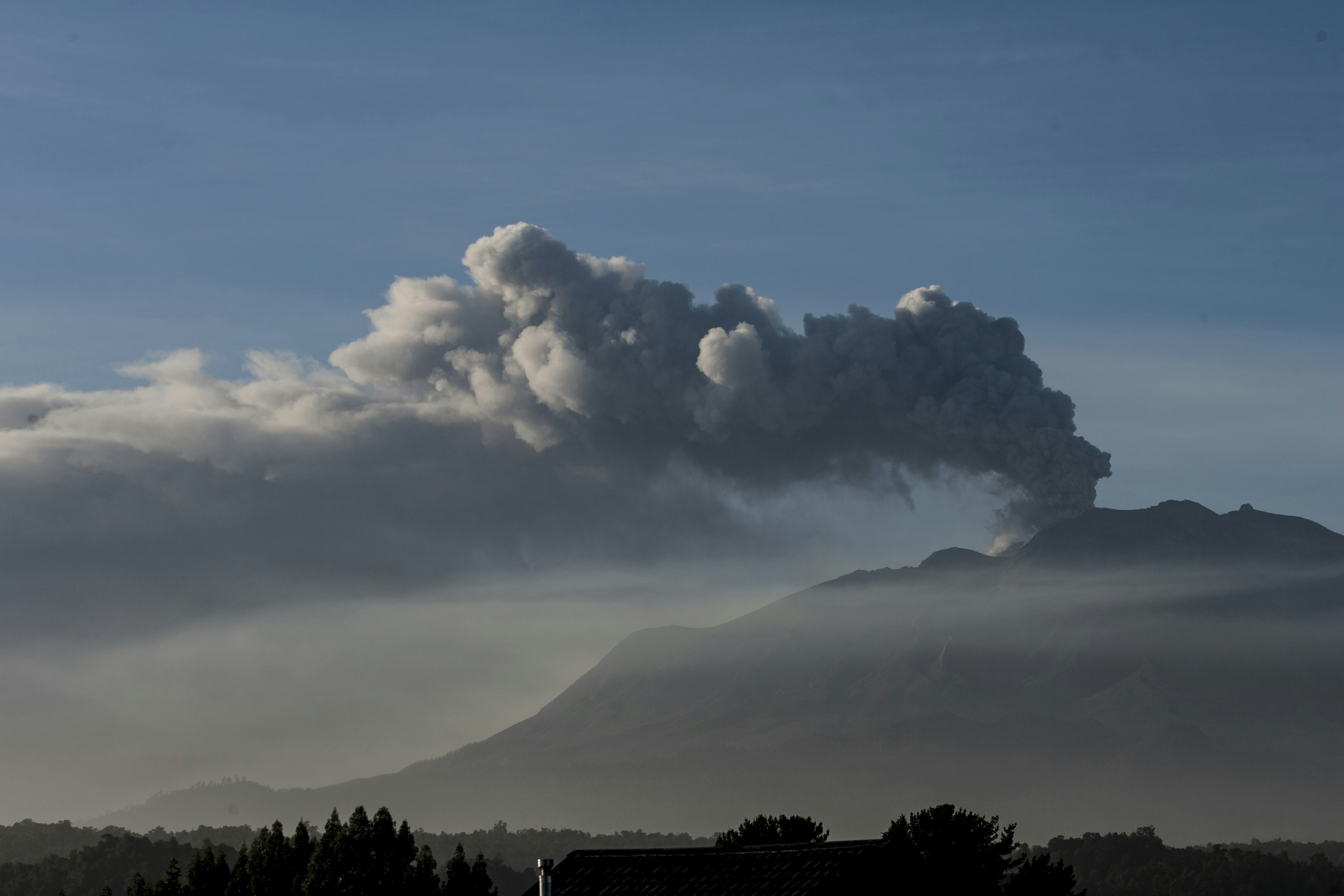 Volcanic ash plume billows from a mountain peak