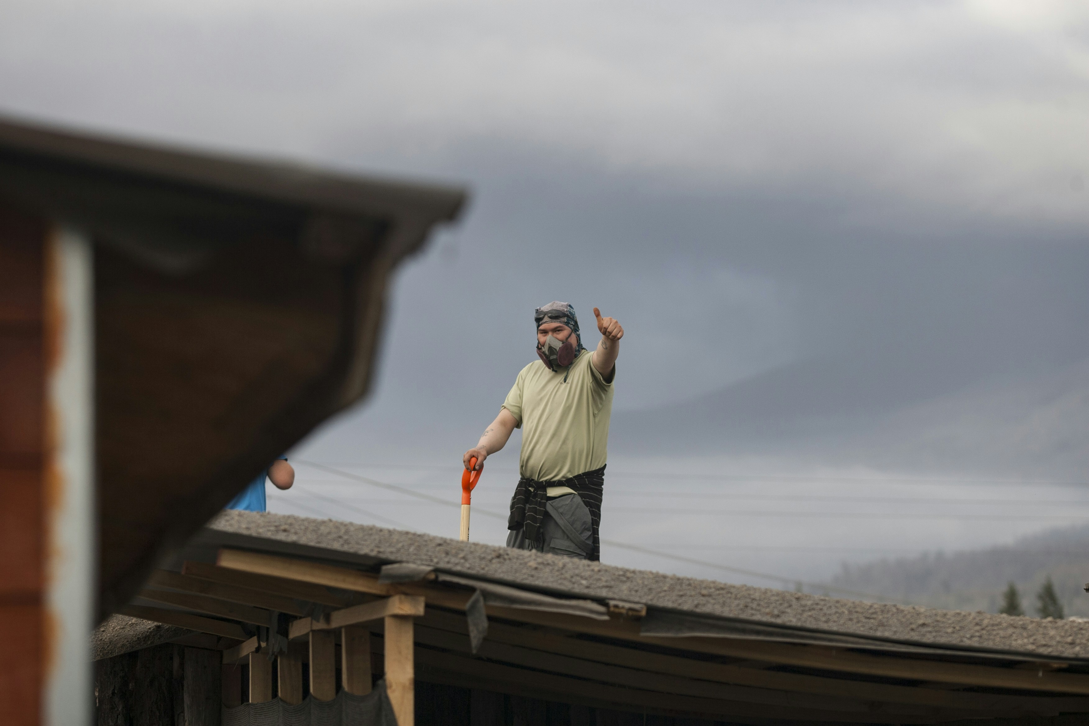 Man on roof waving with shovel