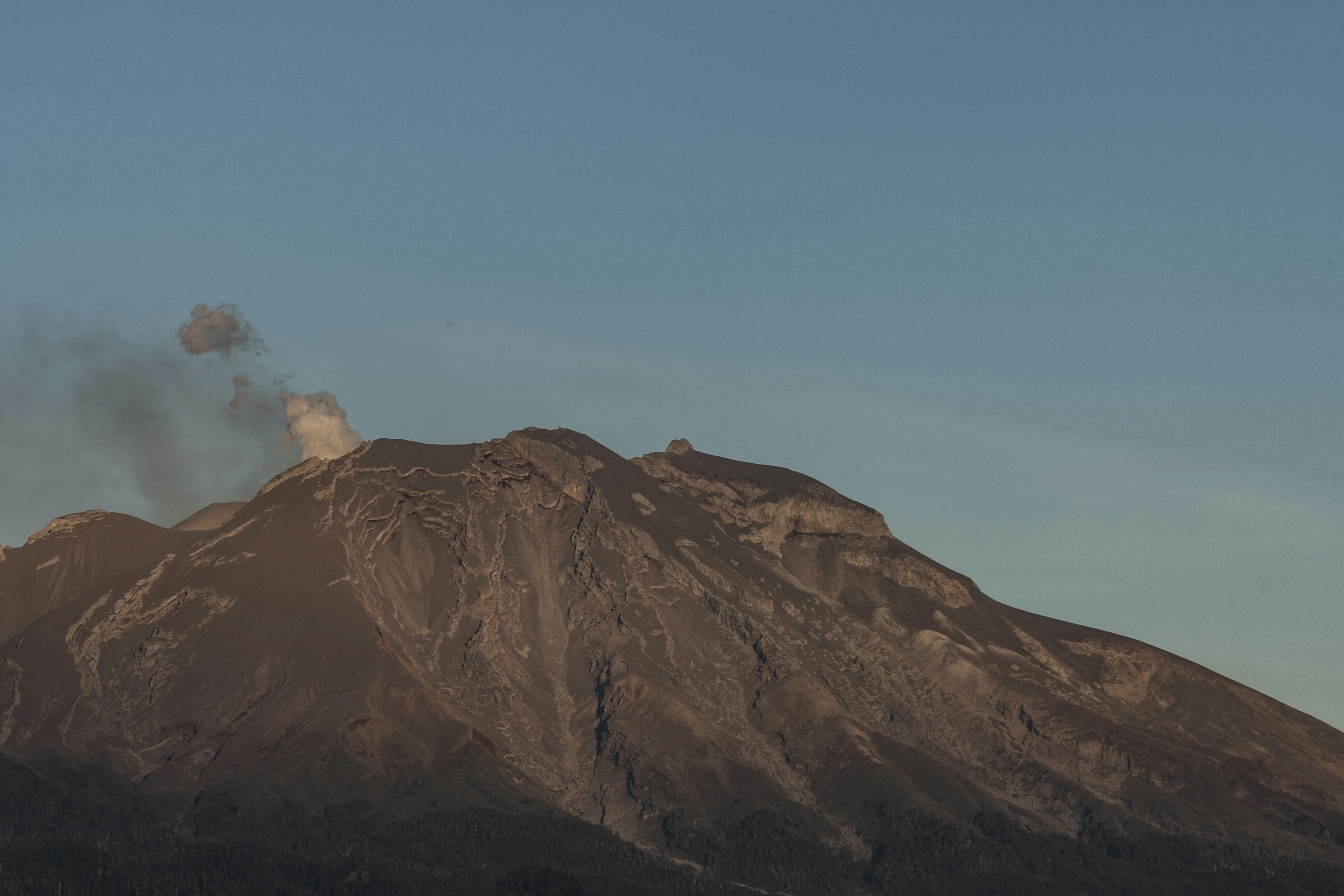 A majestic volcano emitting smoke under a clear blue sky