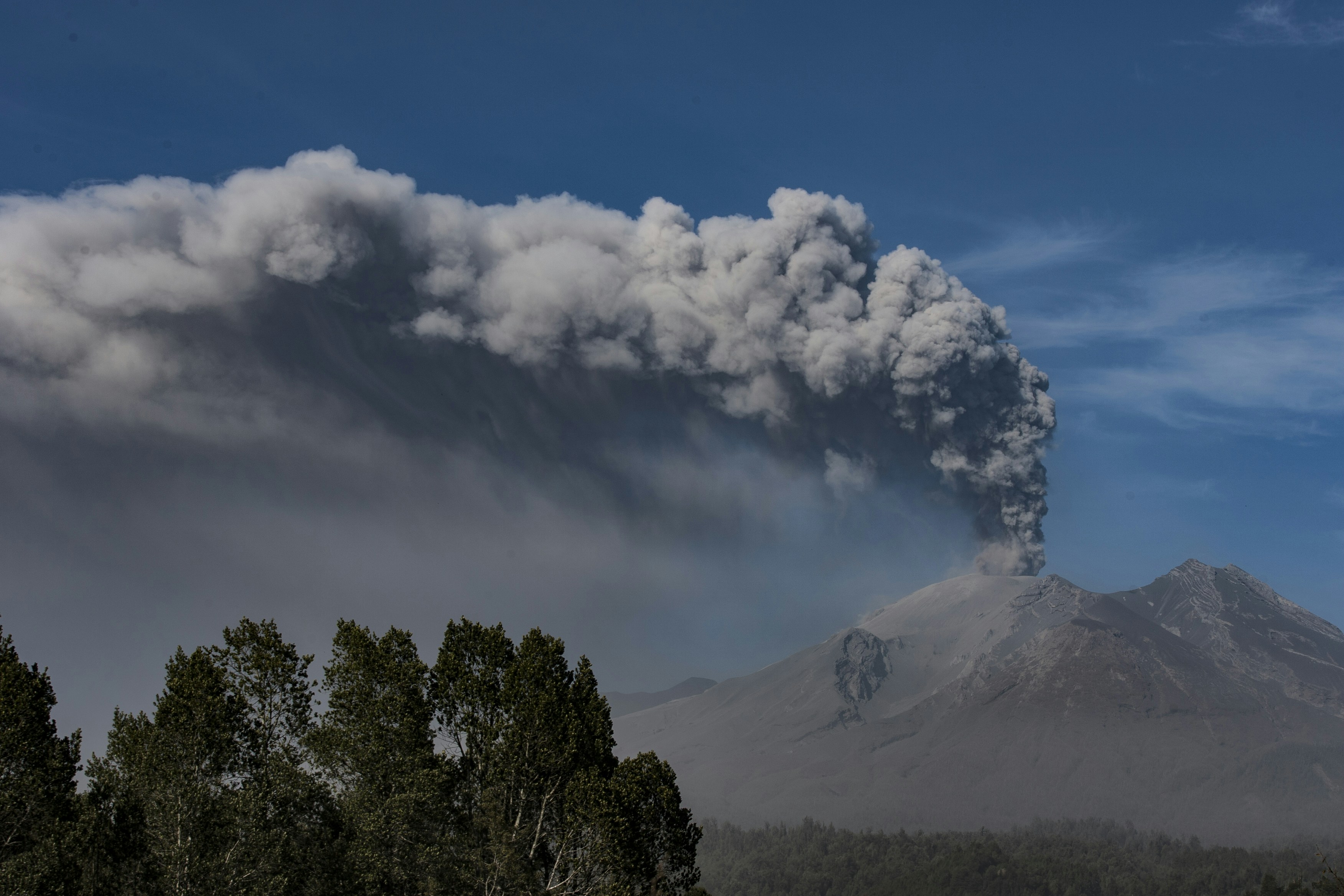 Massive ash plume rising from an erupting volcano