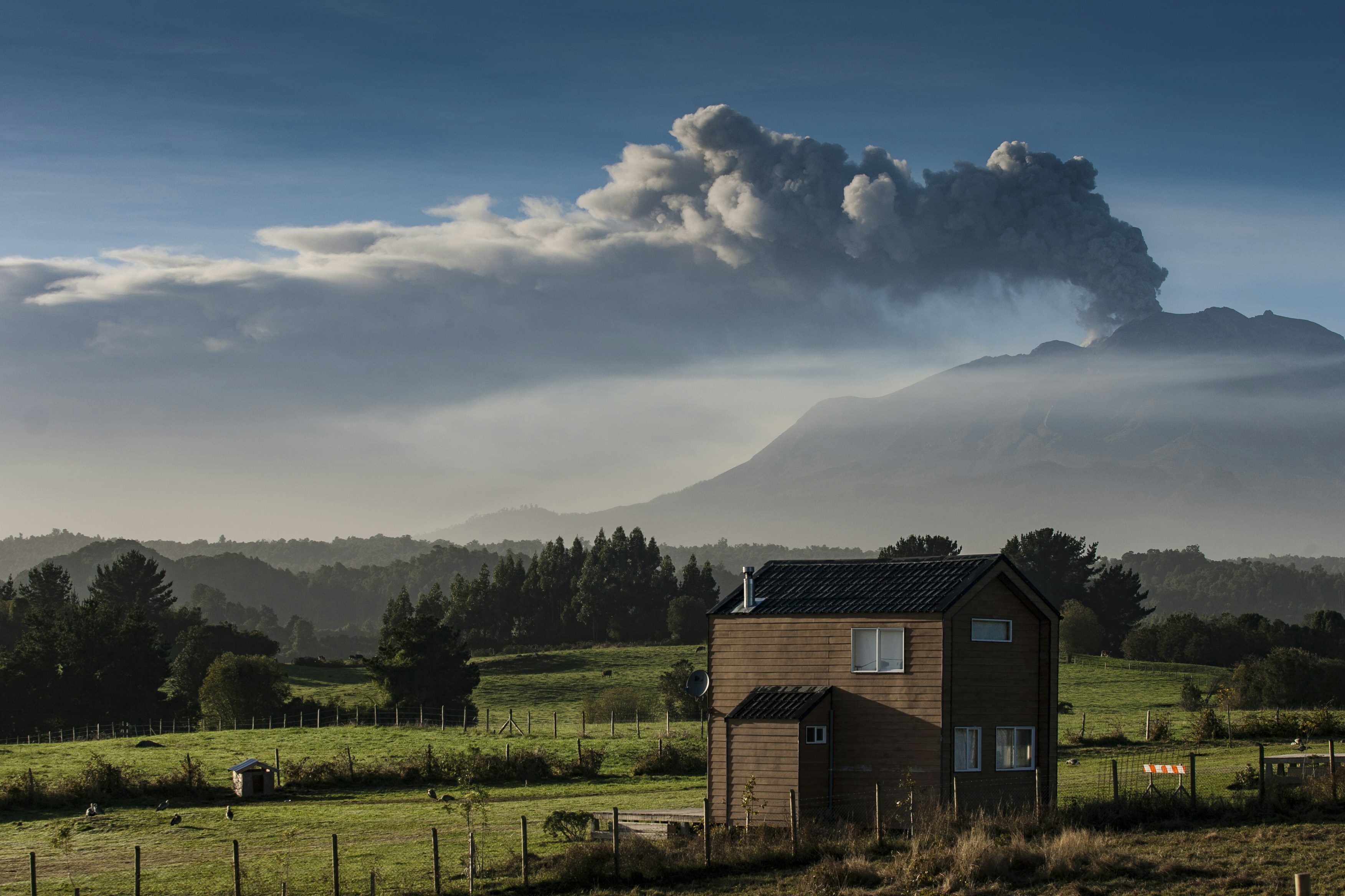 Volcano erupting with smoke plume over landscape.