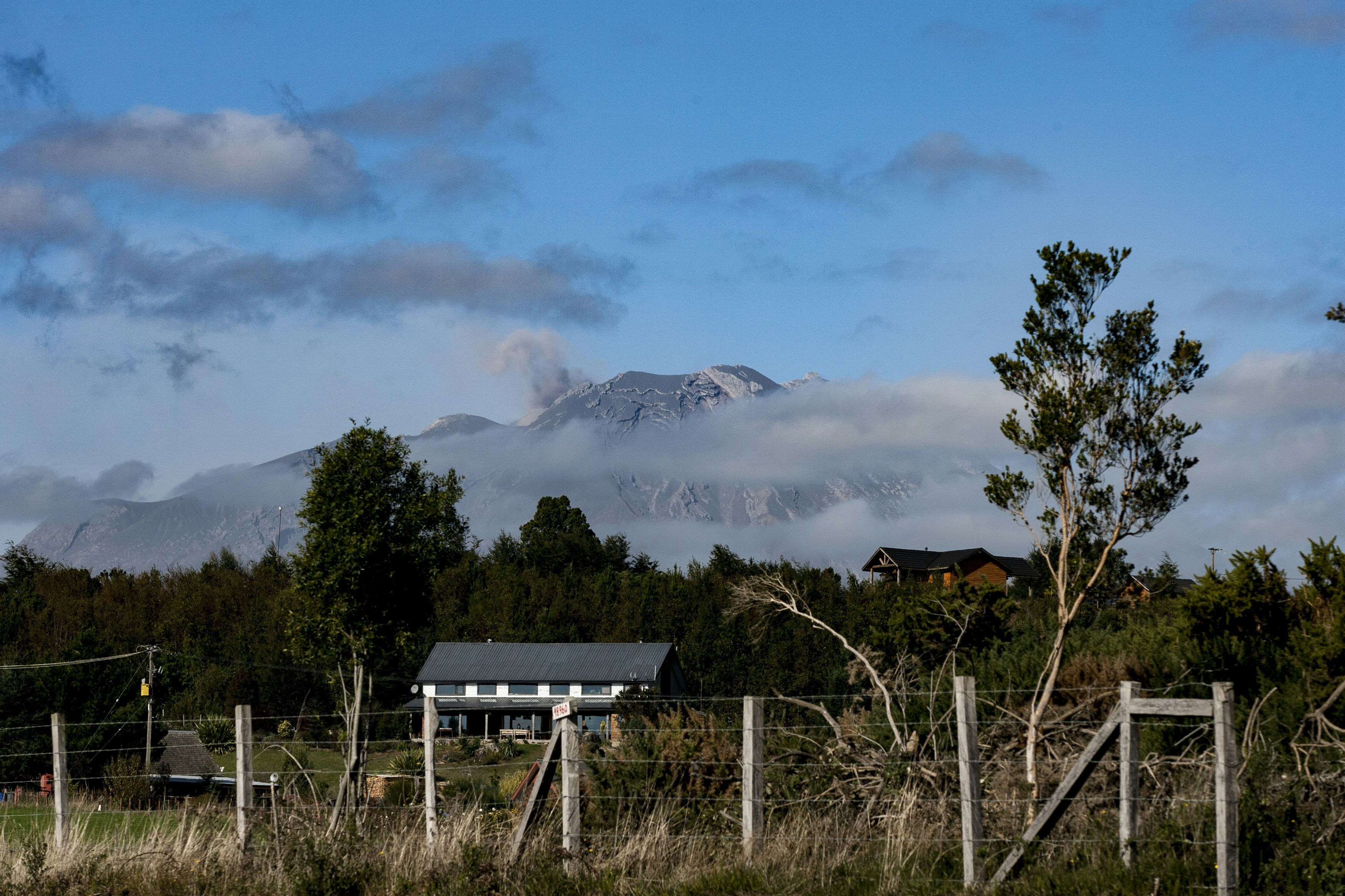 Volcanic smoke rises from a distant mountain peak.