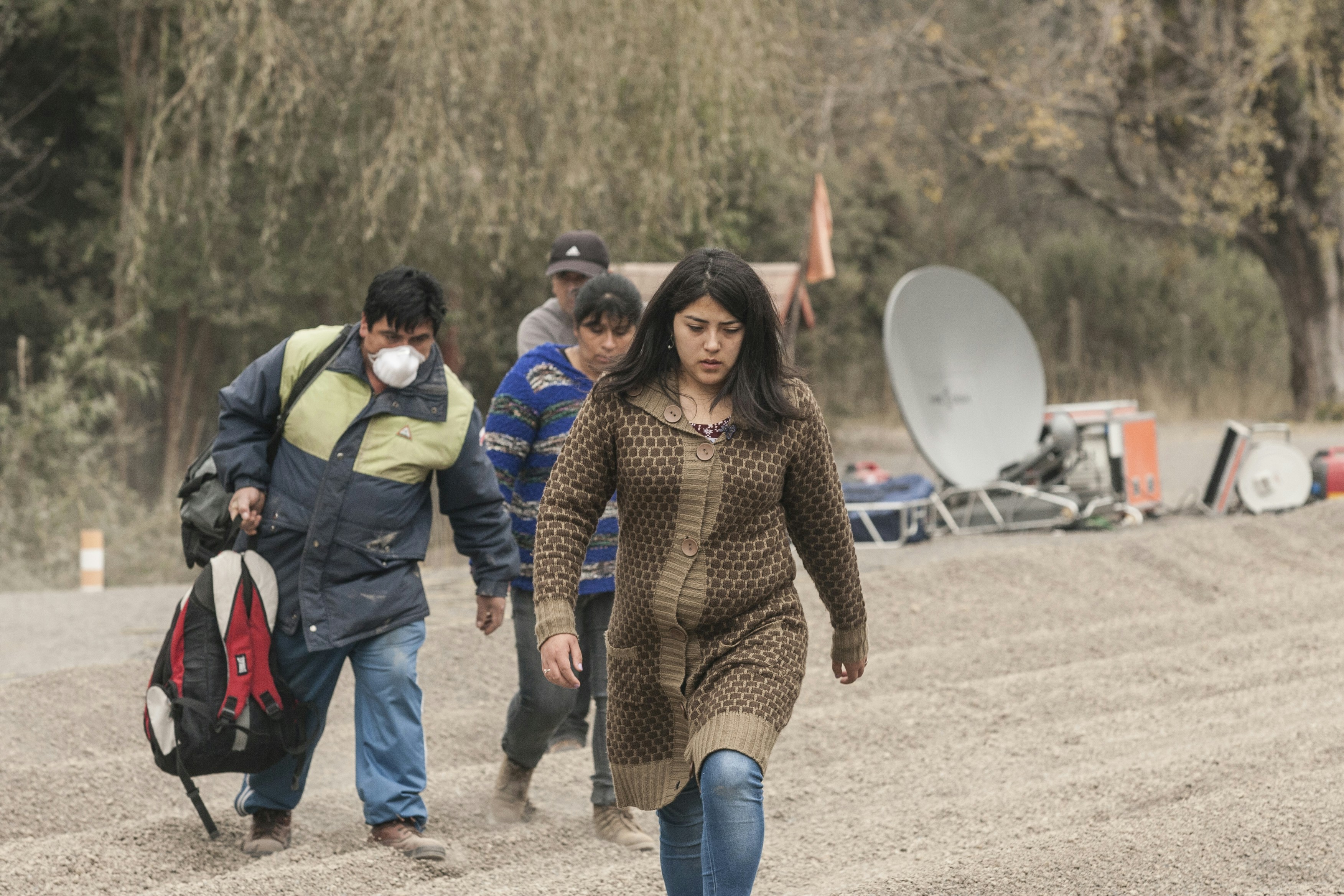 People walk through a dusty, ash-covered landscape