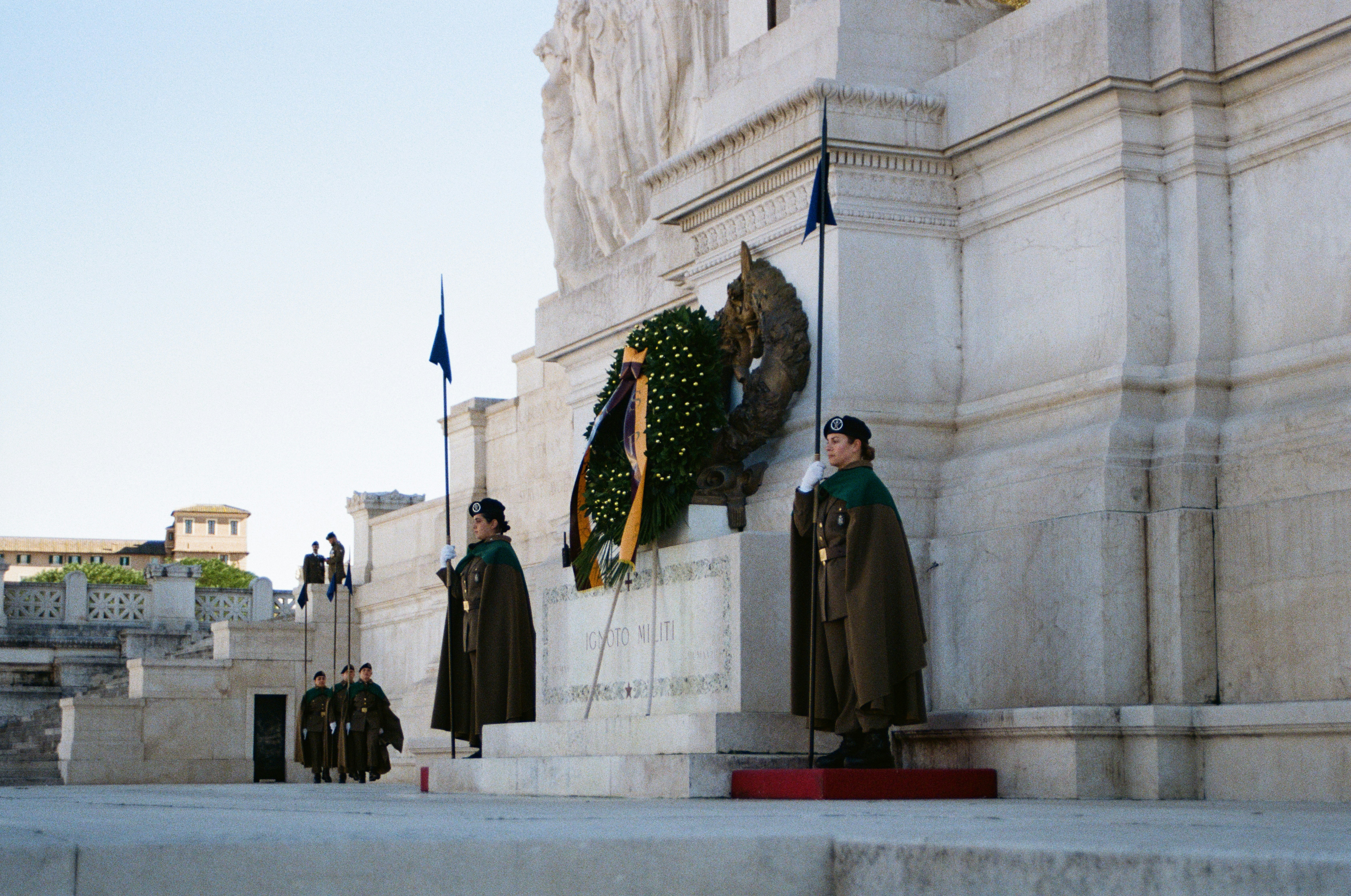 Soldiers in uniform stand guard at a monument