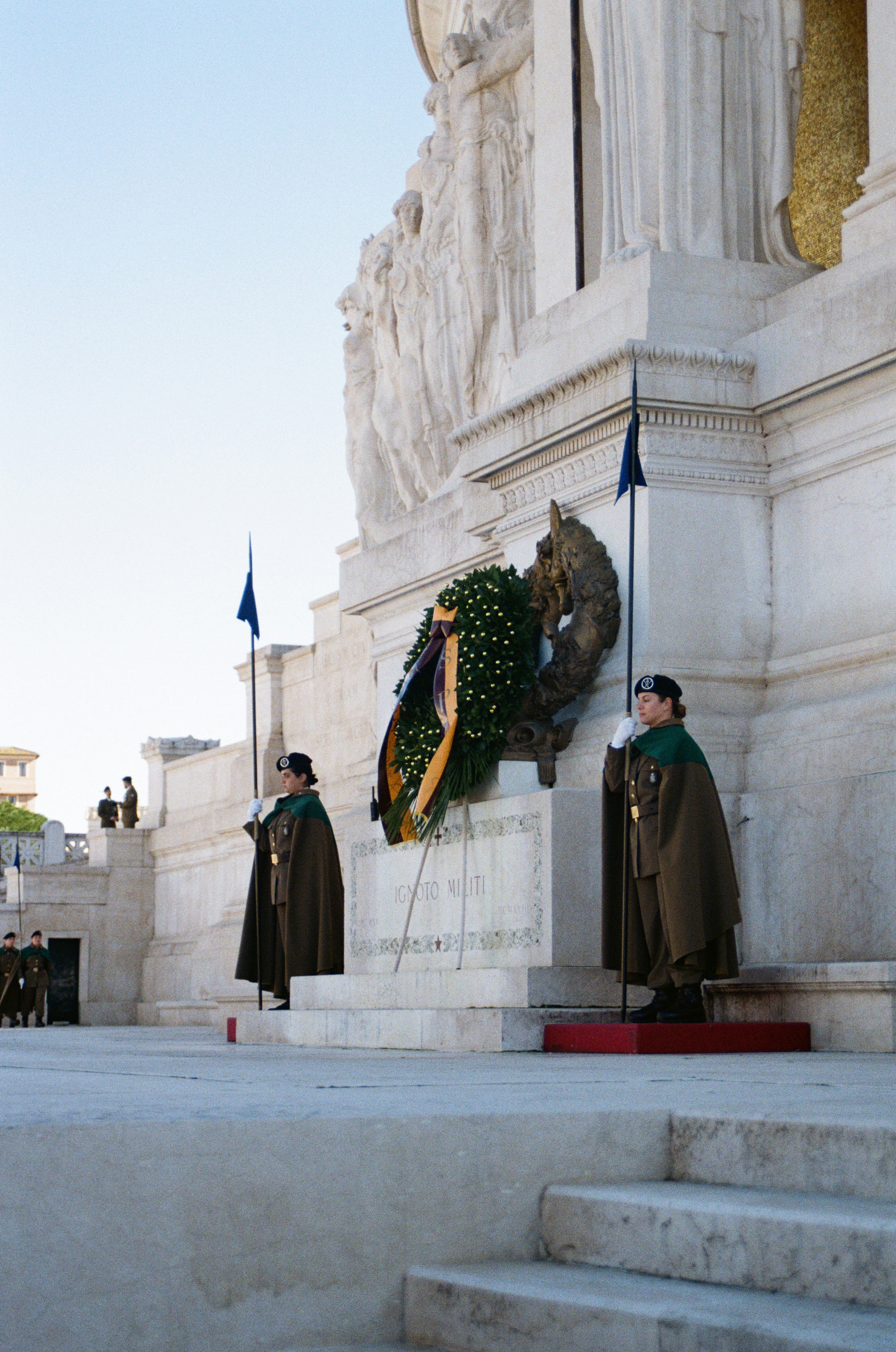 Guards stand at attention near a large wreath.